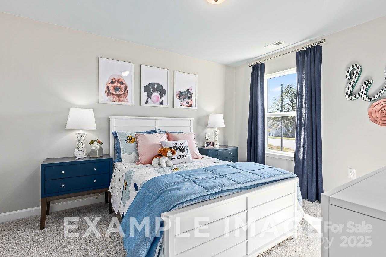 Charming girl's bedroom with twin bed, blue bedding, dog art prints, and window in The Hemlock A by Davidson Homes, Belmont, NC