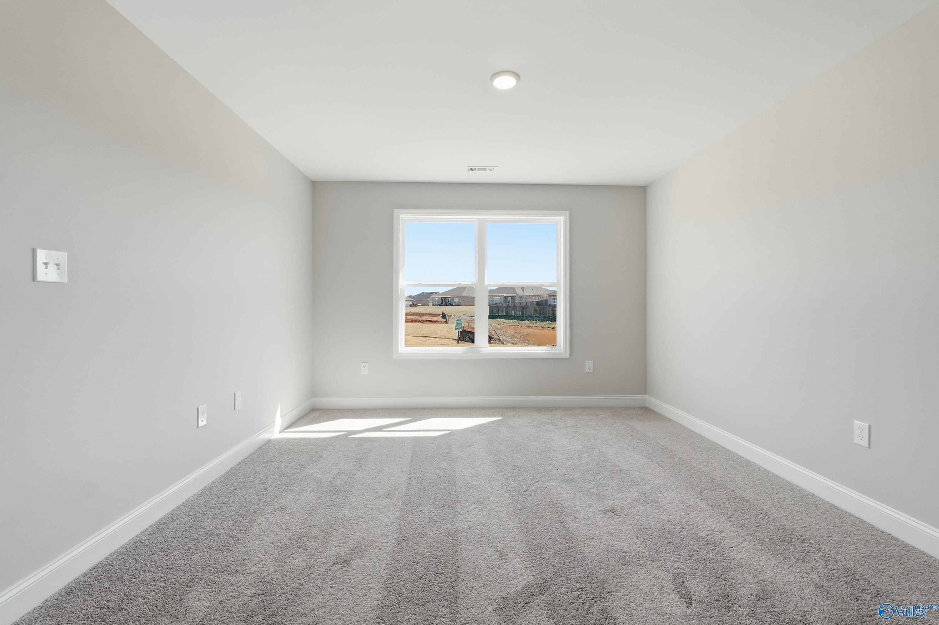 Bright empty bedroom with large window overlooking scenic fields in The Franklin 3-bedroom home, New Market, Alabama