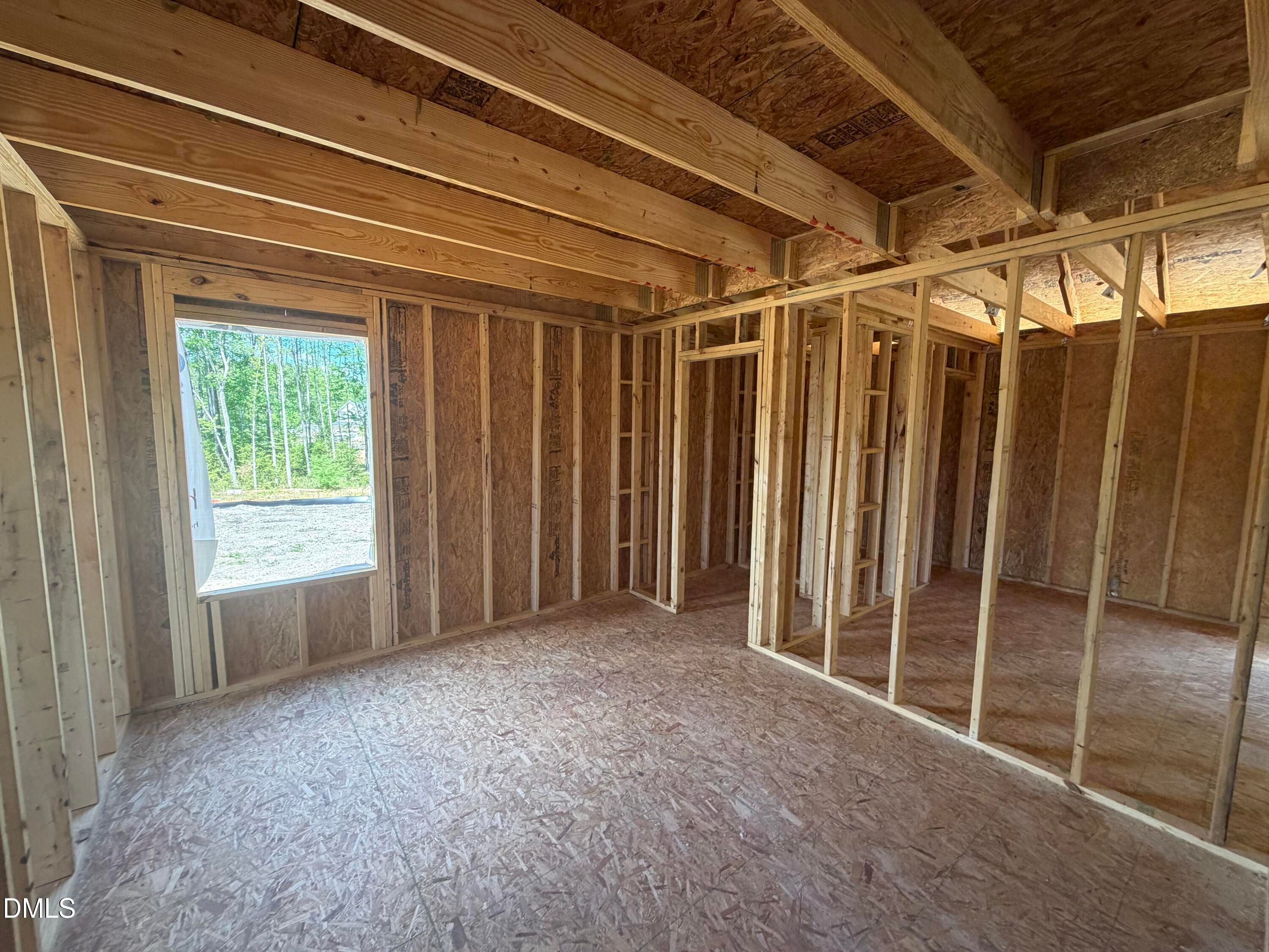 Under-construction wooden framing with OSB walls, exposed joists, and large window to wooded view in Hickory II C home, Lillington NC