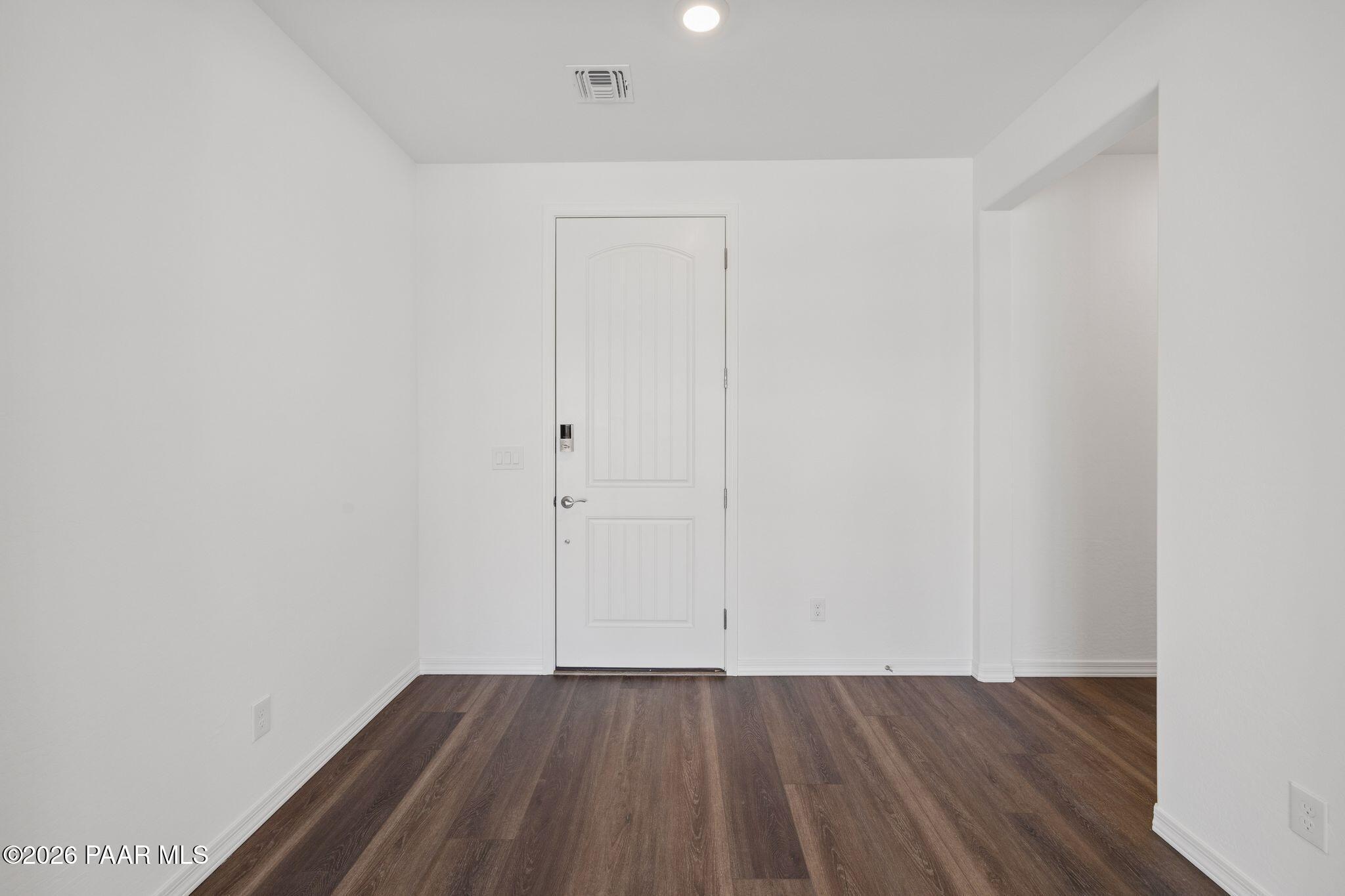 Empty entry foyer featuring white paneled door, hardwood floors, and recessed lighting in Davidson Homes The Monarch A, Prescott, Arizona