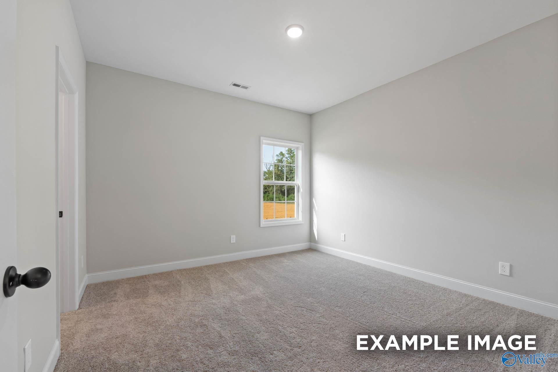 Bright secondary bedroom featuring neutral gray walls, beige carpet, and large window in Davidson Homes Montgomery B, Toney, Alabama