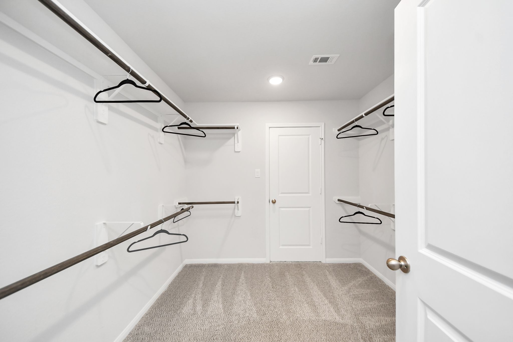Spacious walk-in closet with shelving and carpeted floors at Sunterra in Katy, Texas by Davidson Homes.