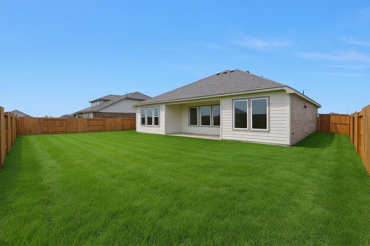 Spacious backyard with covered patio, large windows, and fenced lawn in Davidson Homes The Edward A 3-car garage home, Lago Mar, Texas City