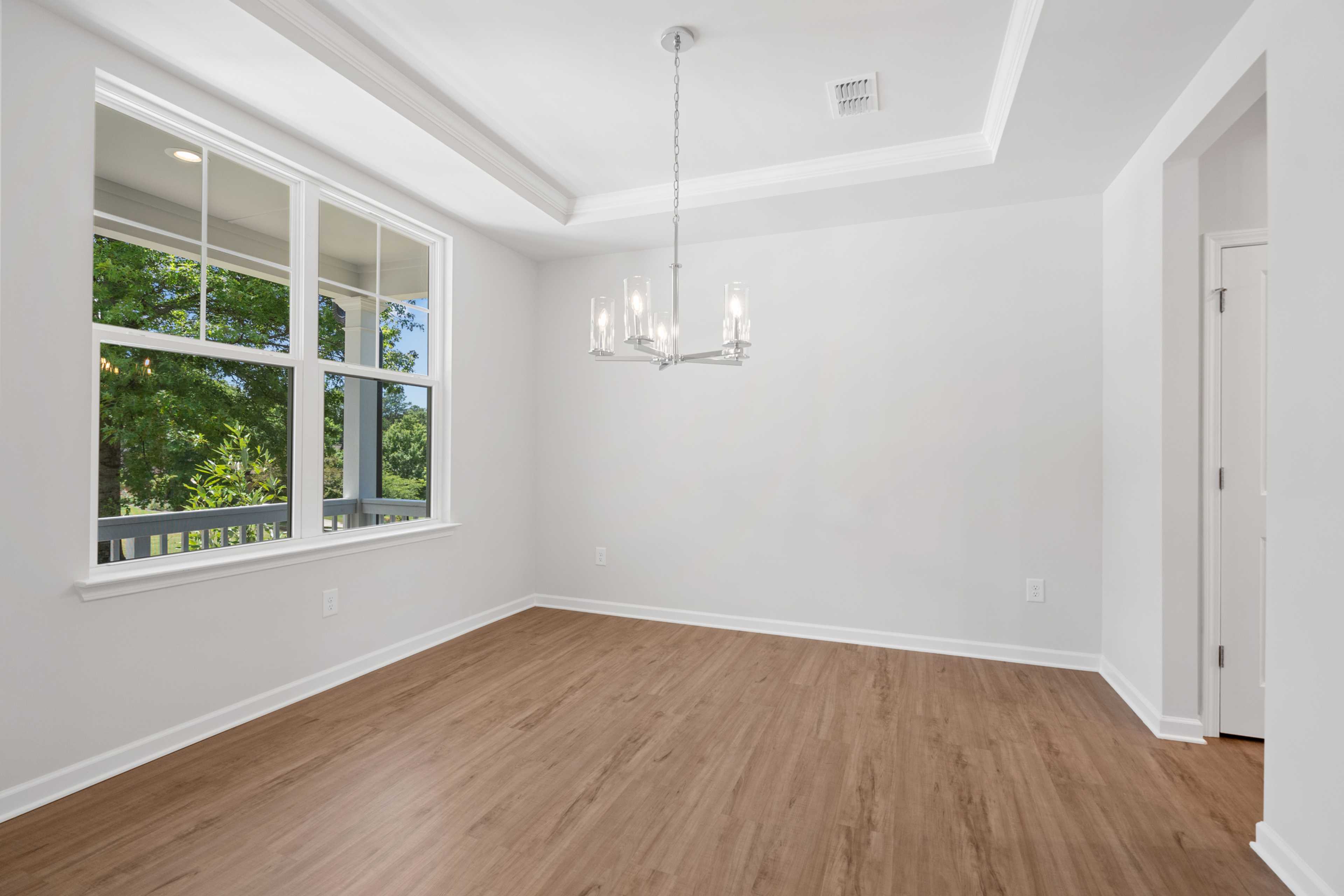 Spacious dining room at Mountainbrook in Cartersville GA featuring hardwood floors, chandelier, and large windows with tree views