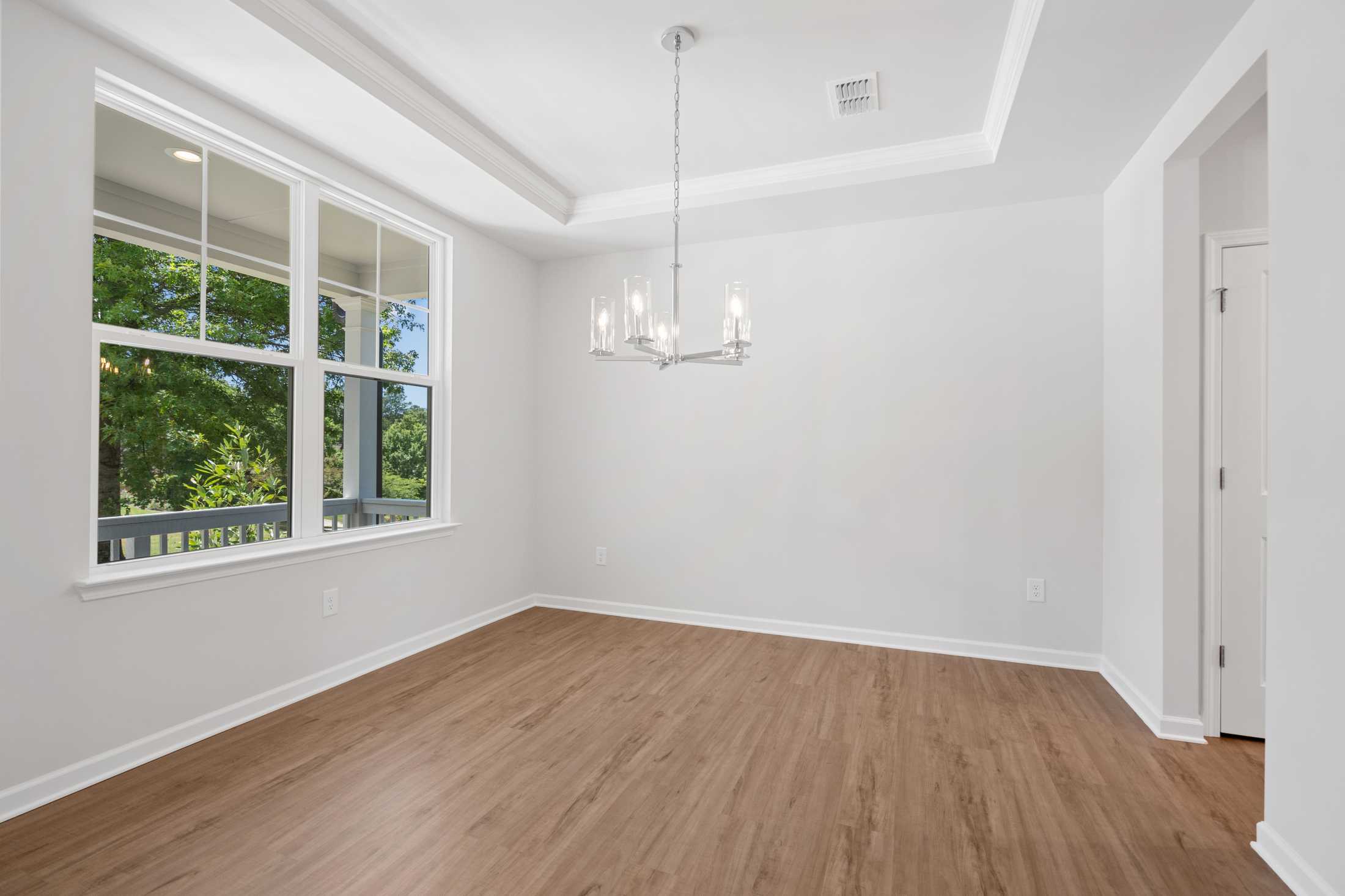 Spacious dining room at Mountainbrook in Cartersville GA featuring hardwood floors, chandelier, and large windows with tree views
