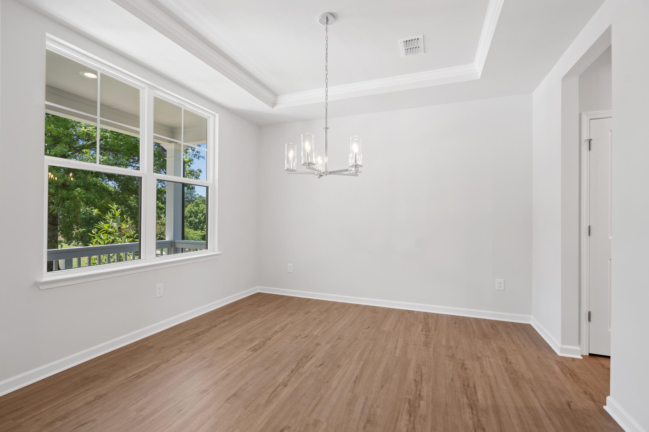 Spacious dining room at Mountainbrook in Cartersville GA featuring hardwood floors, chandelier, and large windows with tree views