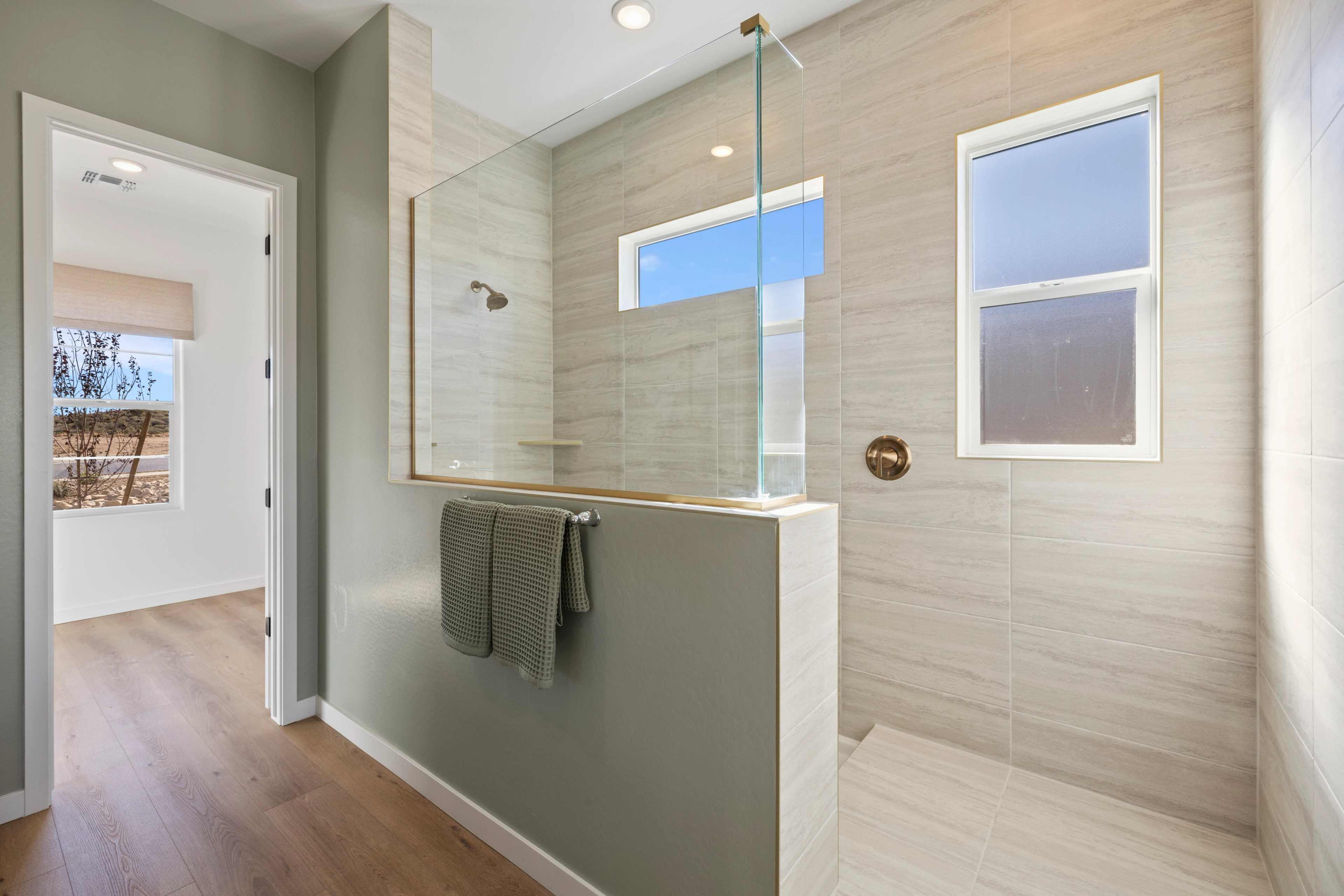 Modern walk-in shower with glass enclosure in Hidden Hills home, Prescott AZ by Davidson Homes featuring tiled walls and natural light