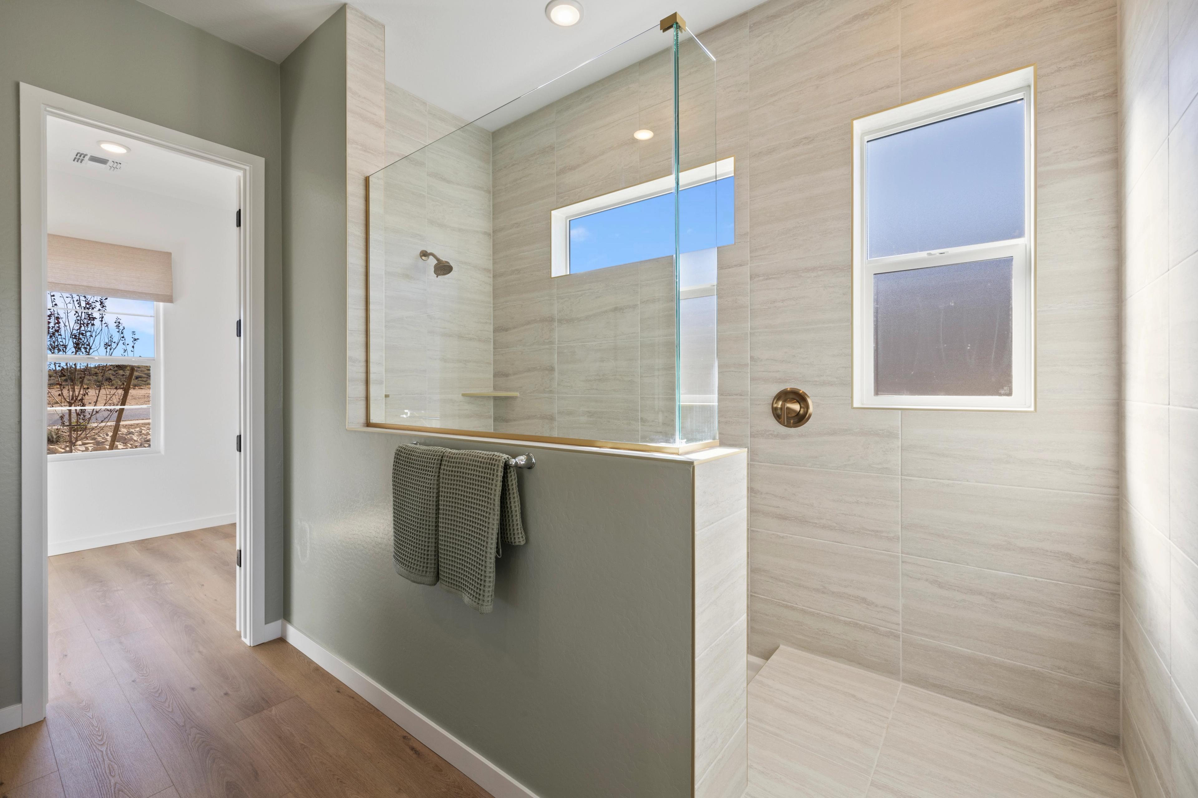Modern walk-in shower with glass enclosure in Hidden Hills home, Prescott AZ by Davidson Homes featuring tiled walls and natural light