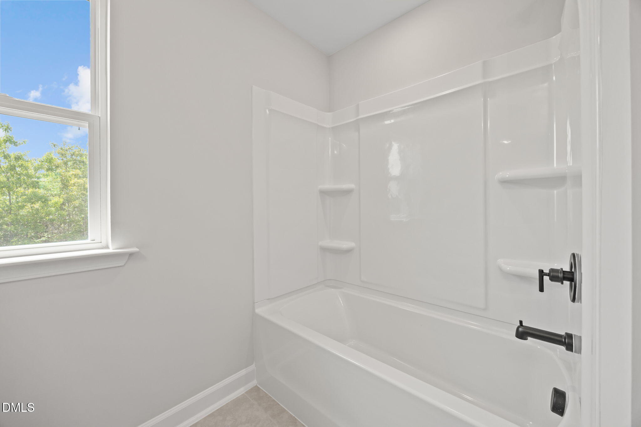 Bright white bathtub shower combo with shelves and black fixtures in Davidson Homes The Willow D, Wendell, North Carolina