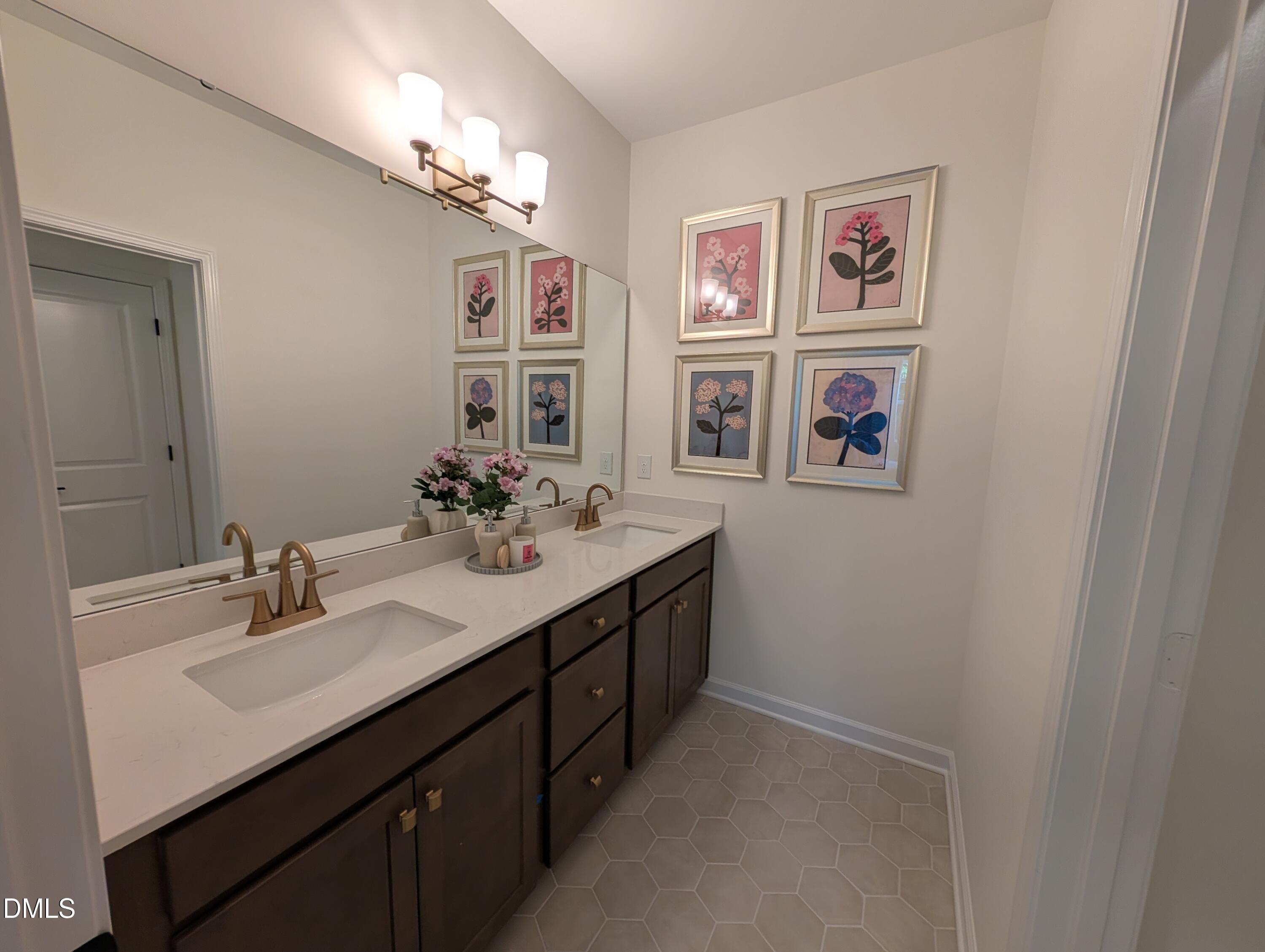 Double vanity bathroom with gold faucets and floral art in The Aspen B floor plan at Wendell Ridge, Wendell, NC.