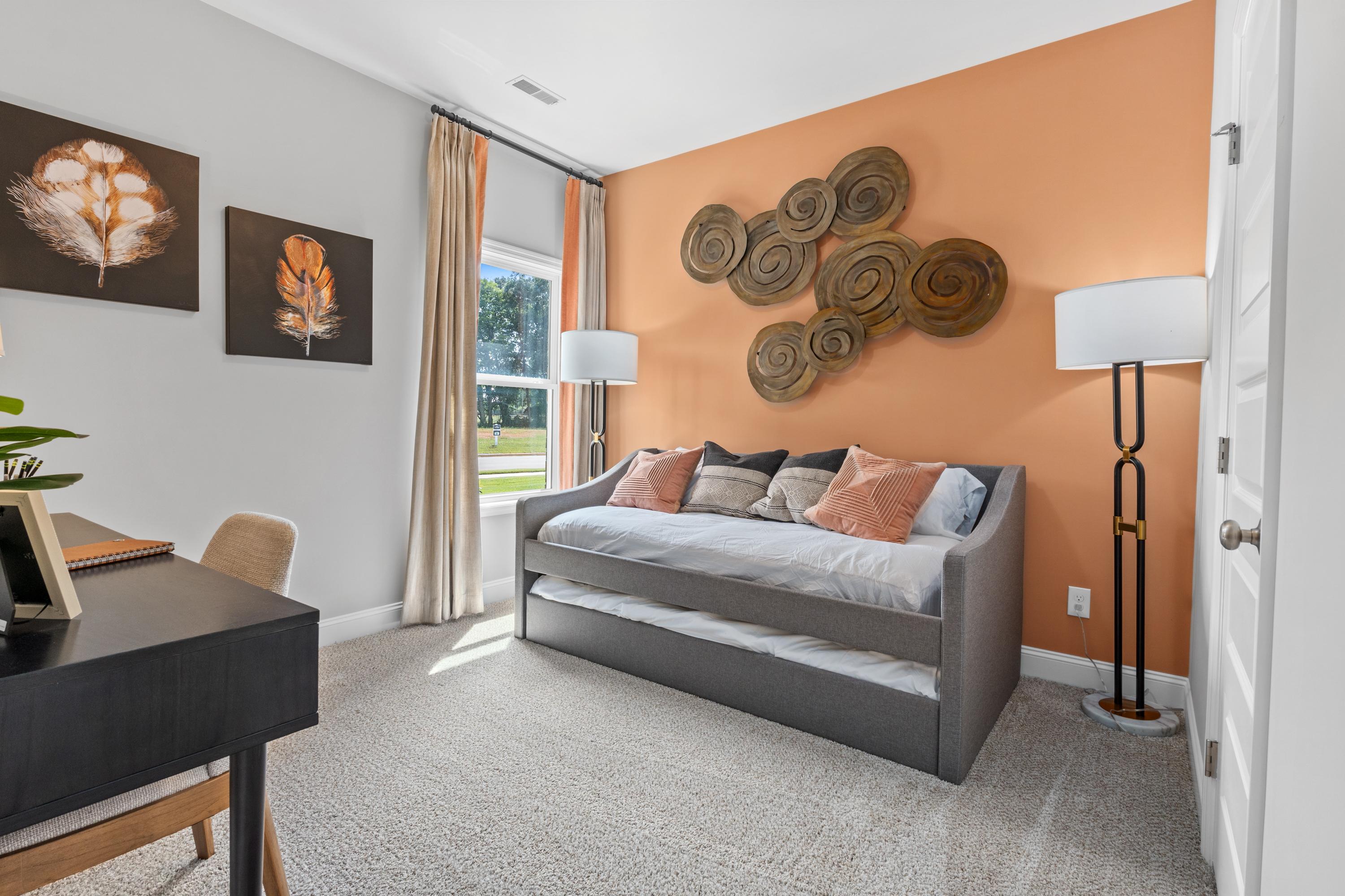 Cozy bedroom in Wood Trail Toney Alabama with gray daybed, orange accent wall, woven decor and desk