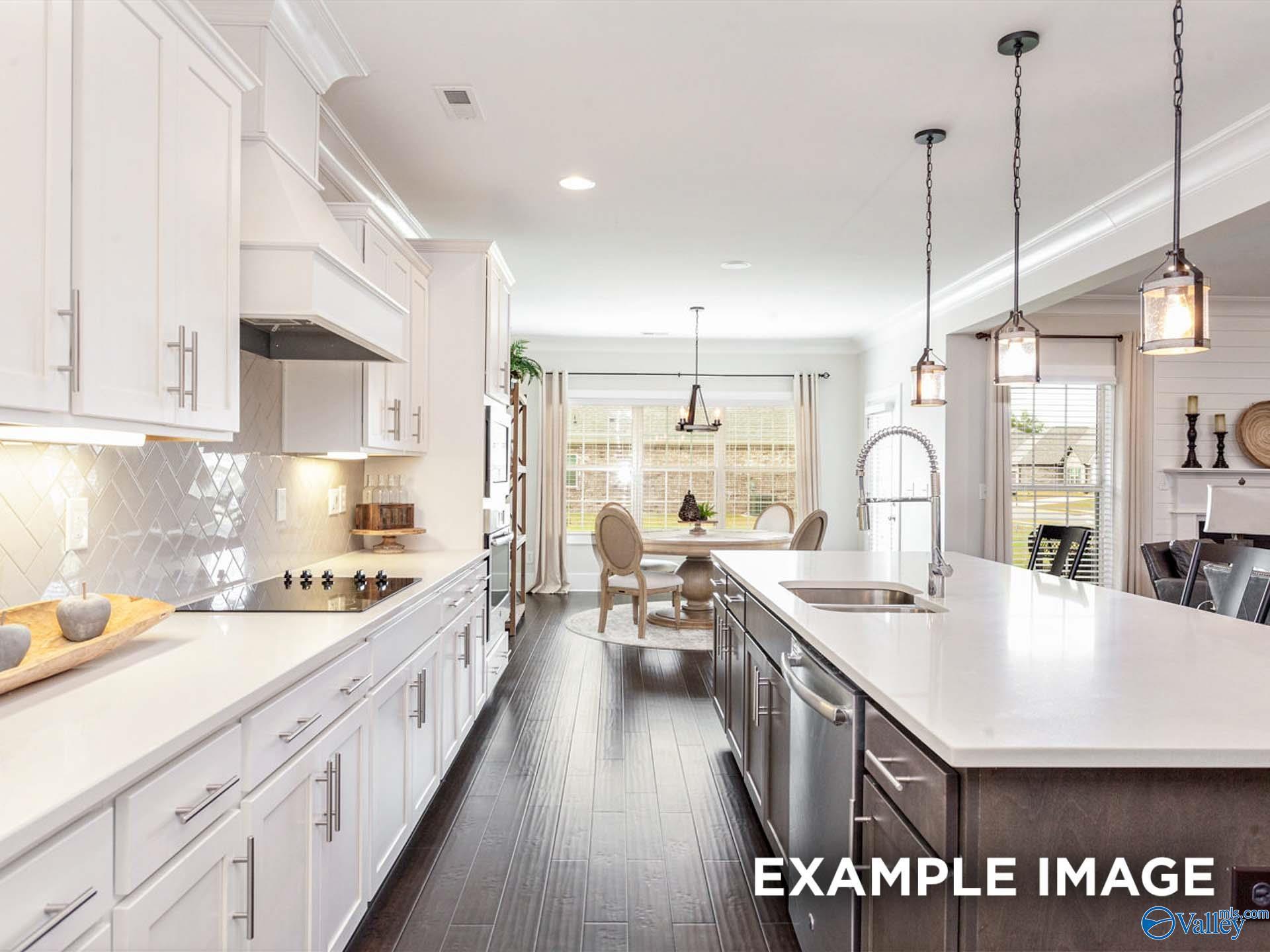 Modern open-concept kitchen with white shaker cabinets, quartz island, stainless appliances in The Finleigh, Meridianville, AL