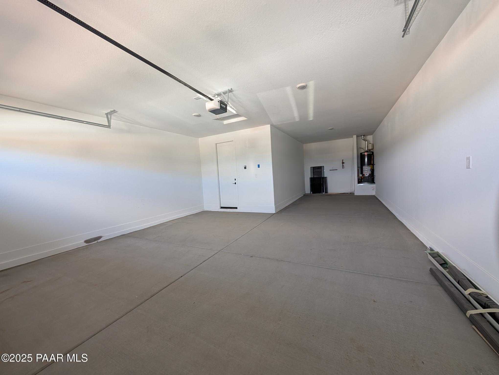 Spacious 3-car garage with concrete floor, storage cabinets, and utility area in Davidson Homes The Sheridan II F, Prescott, Arizona