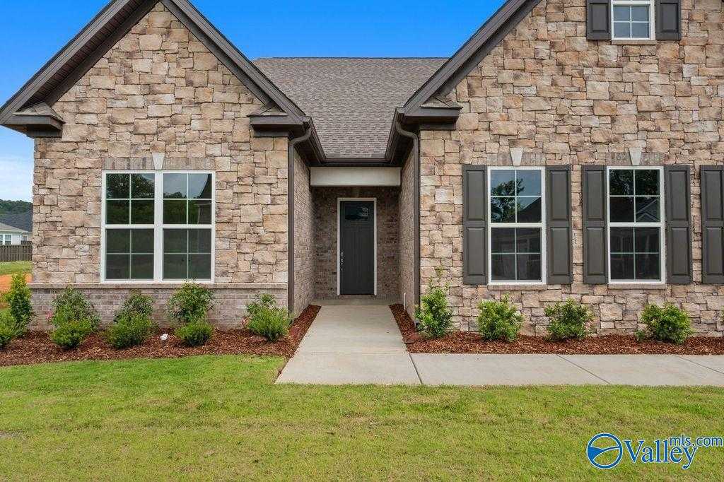 Stone-front 1.5-story home with dark shutters, front door, and landscaped walkway in The Meadows at Hampton Cove, Owens Cross Roads, Alabama - Evermore Homes The Oxford