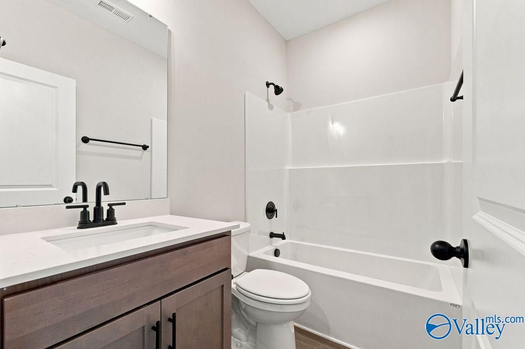 Modern bathroom with vanity, white quartz countertop, and tub-shower combo in The Camilla C home at The Retreat at Cain Park.