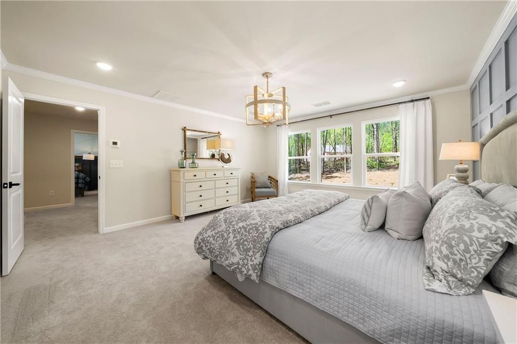 Elegant master bedroom with king bed, gray bedding, chandelier, and large windows in Davidson Homes The Willow B, Riverwood, Dallas, GA