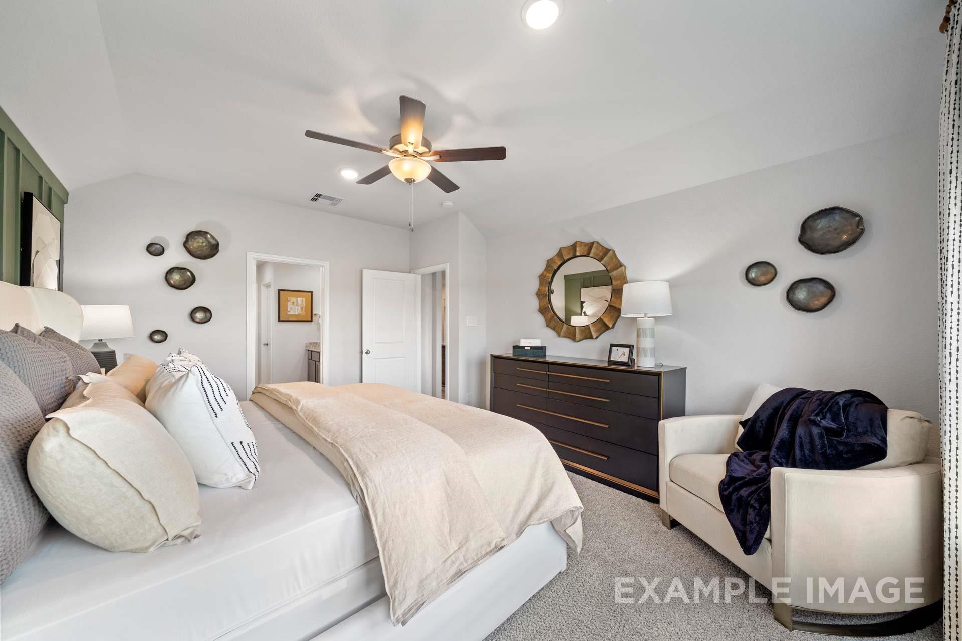 Bright primary bedroom with vaulted ceiling, ceiling fan, and sitting chair in Davidson Homes Acadia A floor plan, Texas City