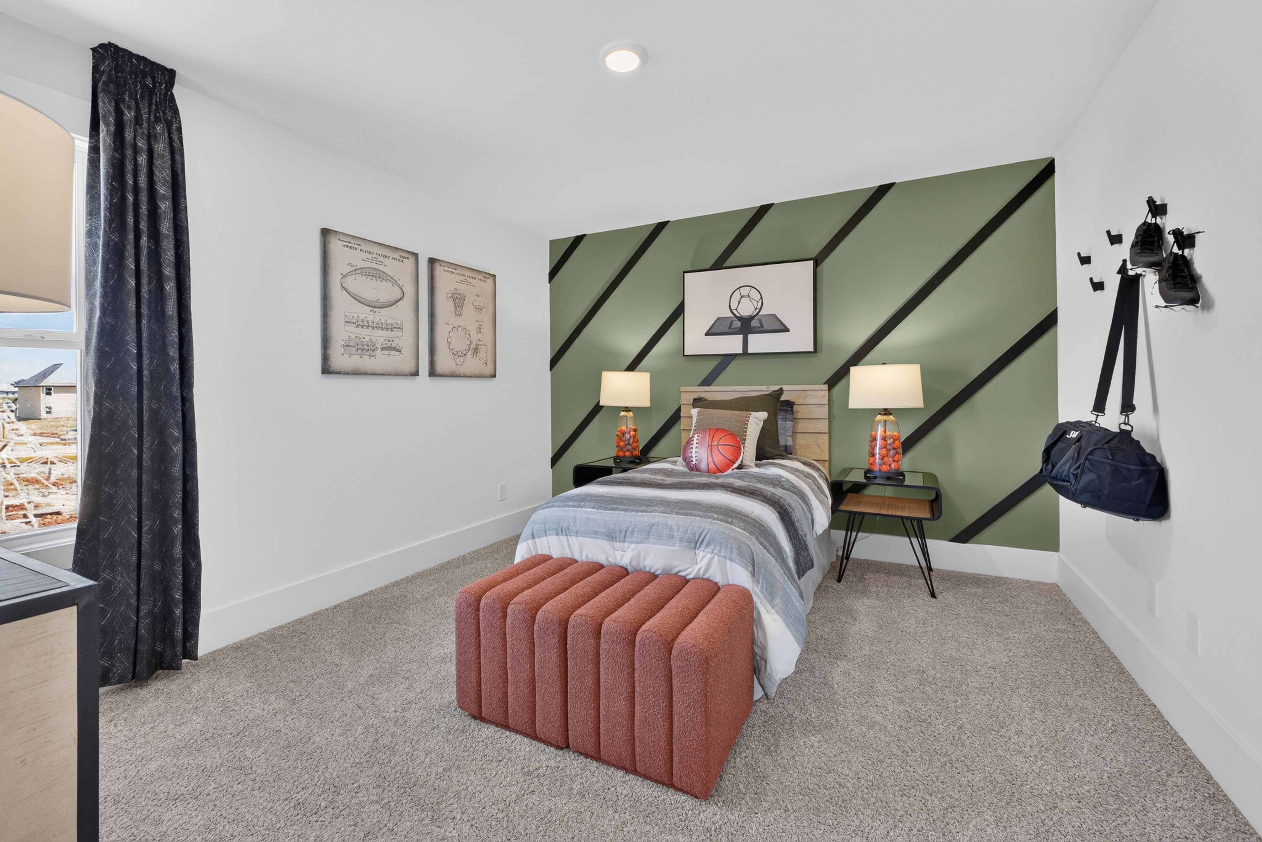 Sports-themed bedroom with green accent wall at Evergreen Mill by Davidson Homes in Madison, Alabama