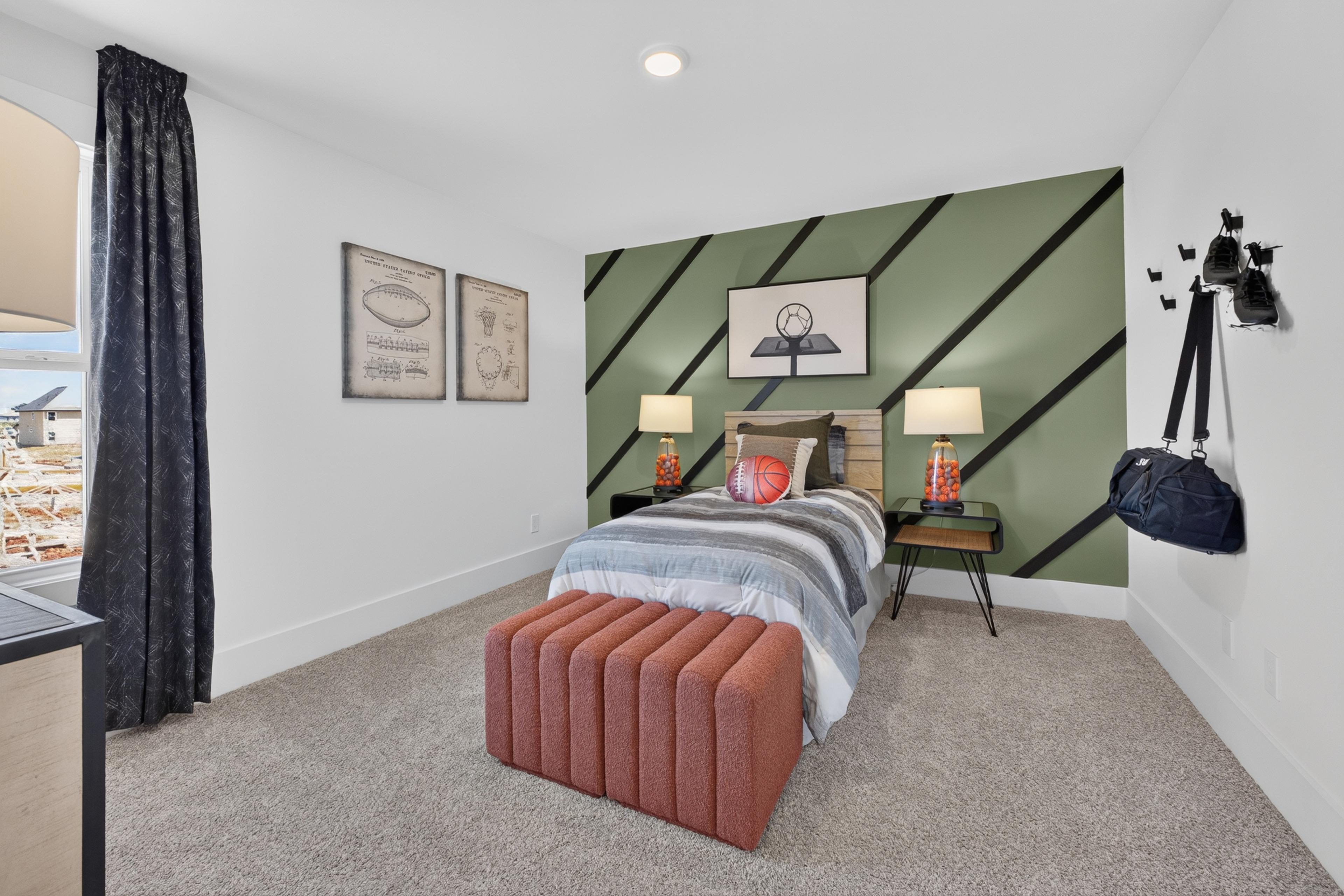 Sports-themed bedroom with green accent wall at Evergreen Mill by Davidson Homes in Madison, Alabama