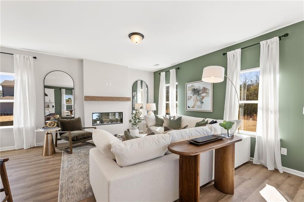 Cozy living room with white sectional sofa, linear gas fireplace, arched mirror, and green accent wall in Davidson Homes The Rabun B, Canton, Georgia