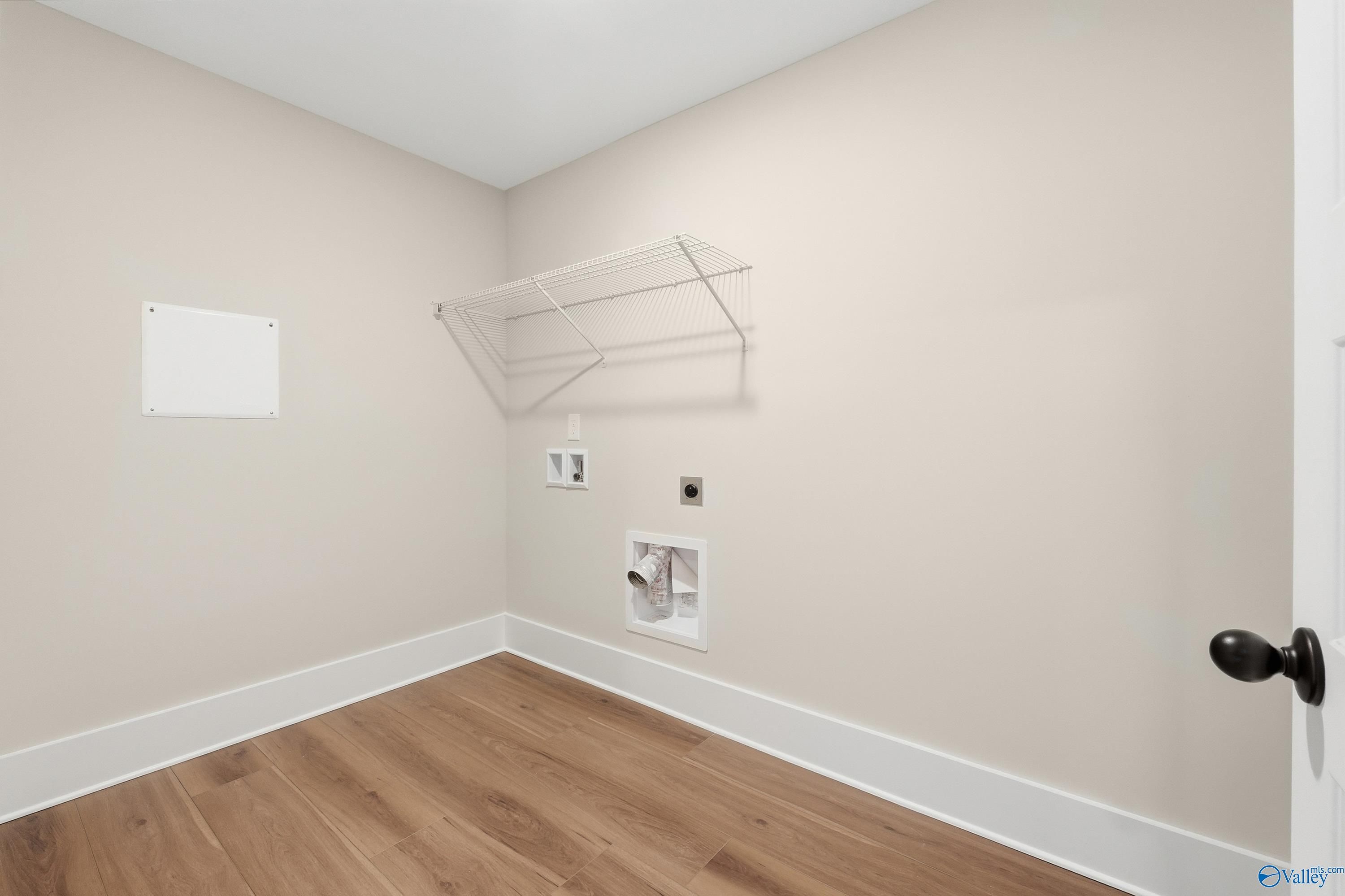 Functional laundry room featuring beige walls, hardwood floors, washer/dryer hookups in Davidson Homes The Shelby A, Athens, Alabama
