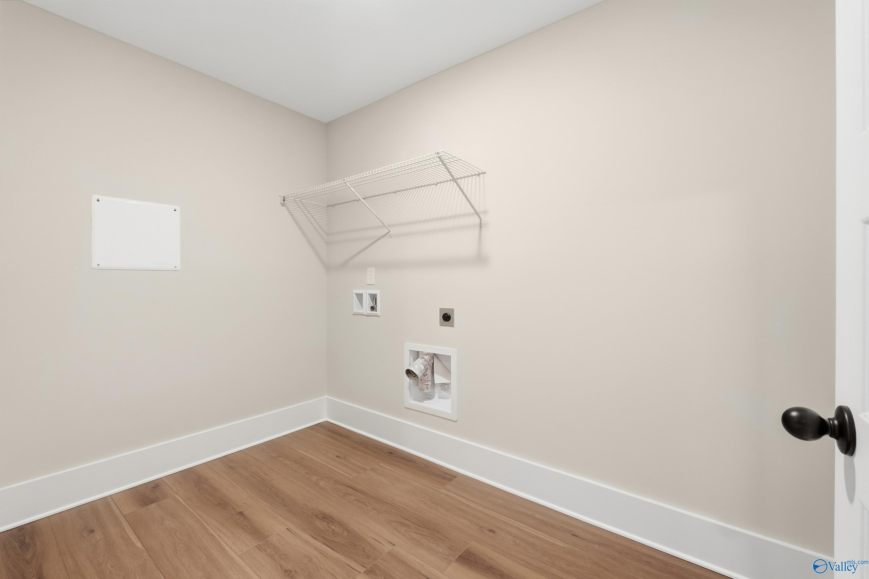 Functional laundry room featuring beige walls, hardwood floors, washer/dryer hookups in Davidson Homes The Shelby A, Athens, Alabama
