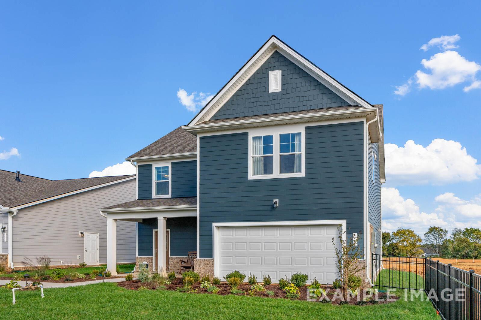Two-story Gordon C home elevation in navy blue siding, gabled roof, 2-car garage, front porch, and lush landscaping