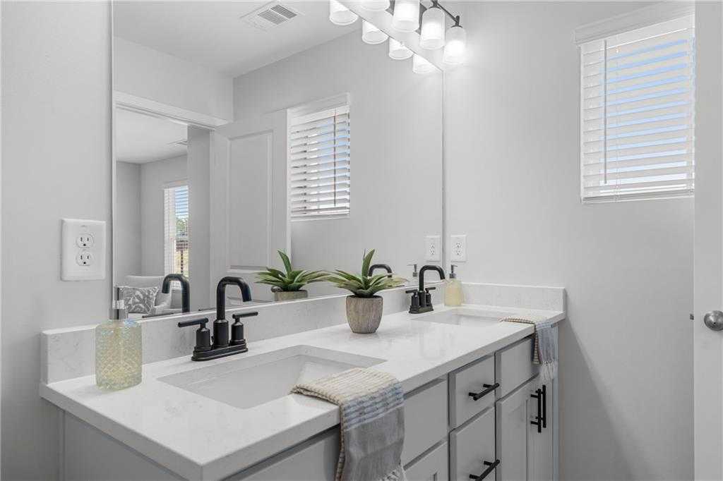Modern double vanity bathroom with white quartz countertop, black faucets, plants in Davidson Homes The Durant A, Emerson, GA