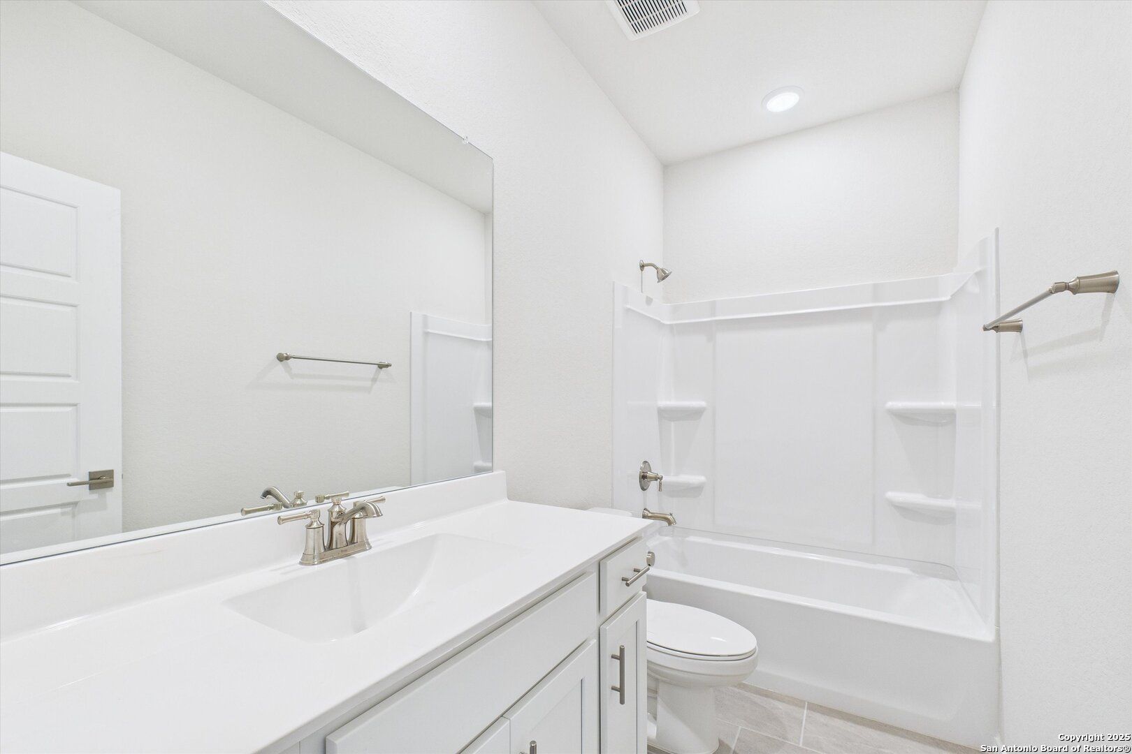 Bright white secondary bathroom with soaking tub, vanity sink, and mirror in Davidson Homes The Asheville K, Bricewood, San Antonio