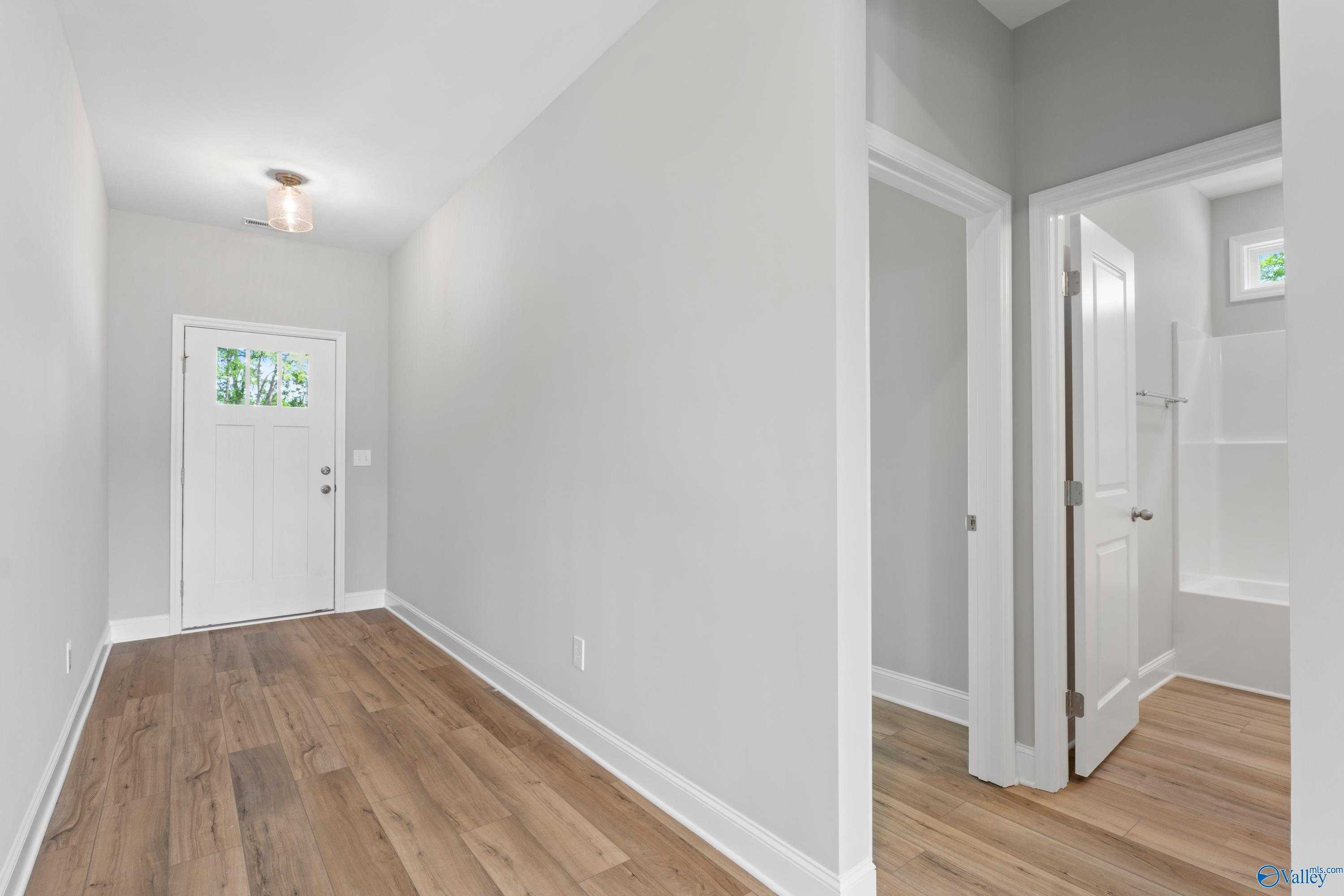 Welcoming entry foyer with white front door, gray walls, hardwood floors in Davidson Homes The Chelsea B, New Market, Alabama