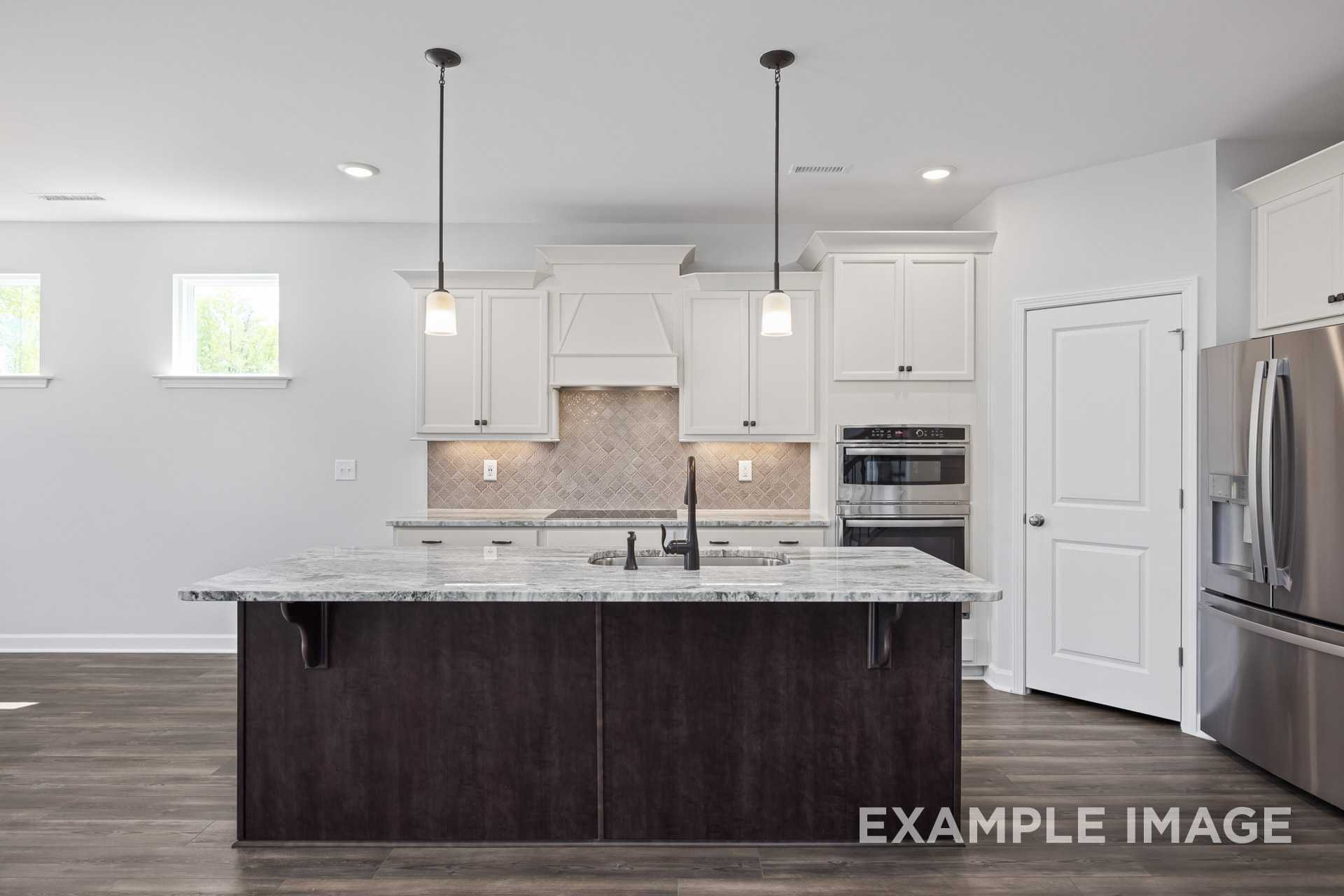 Modern kitchen in The Grace C by Davidson Homes featuring white shaker cabinets, large quartz island, and stainless steel appliances