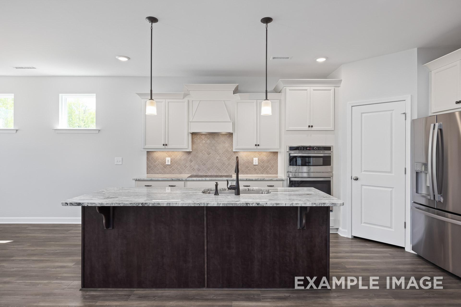 Modern kitchen in The Grace C by Davidson Homes featuring white shaker cabinets, large quartz island, and stainless steel appliances