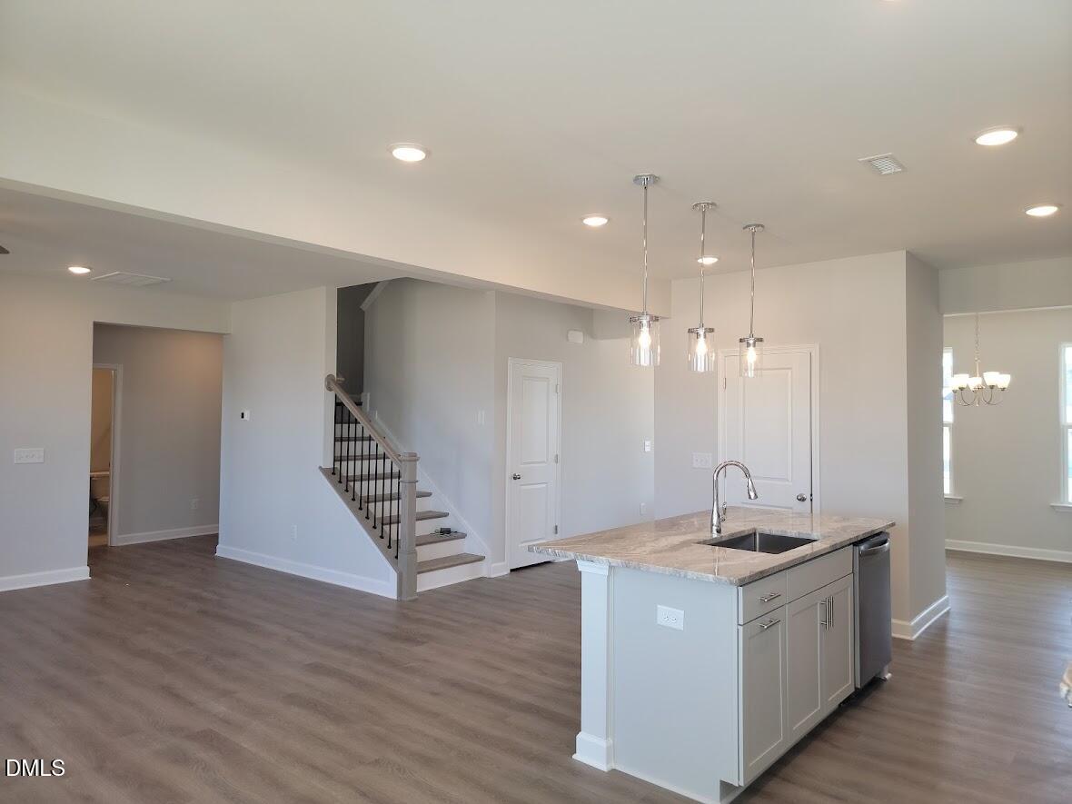 Open-concept kitchen with white island, pendant lights, and staircase in 5-bedroom Davidson Homes The Willow G, Angier, NC