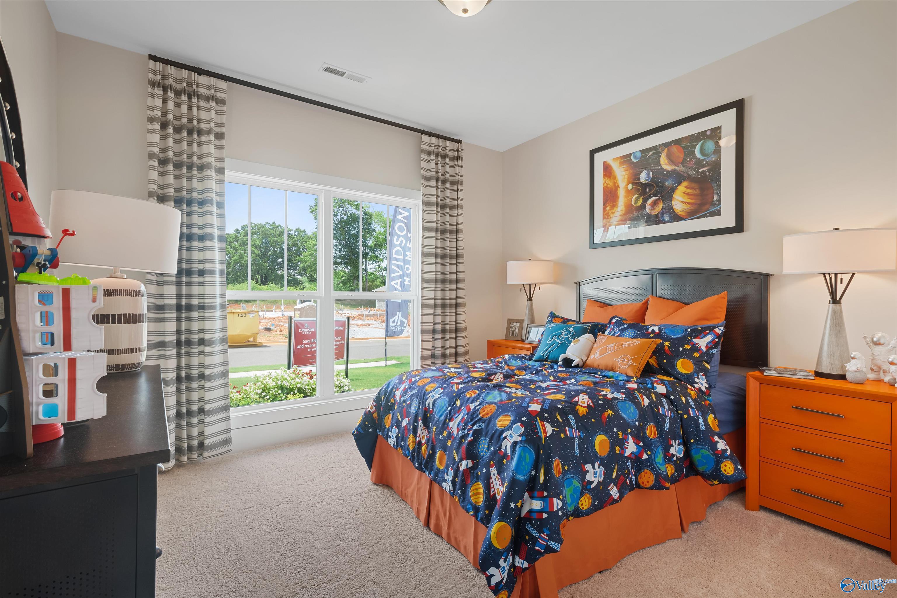 Fun space-themed child's bedroom with galaxy bedding, rocket lamp, and dresser overlooking green landscape in The Everett, New Market, Alabama