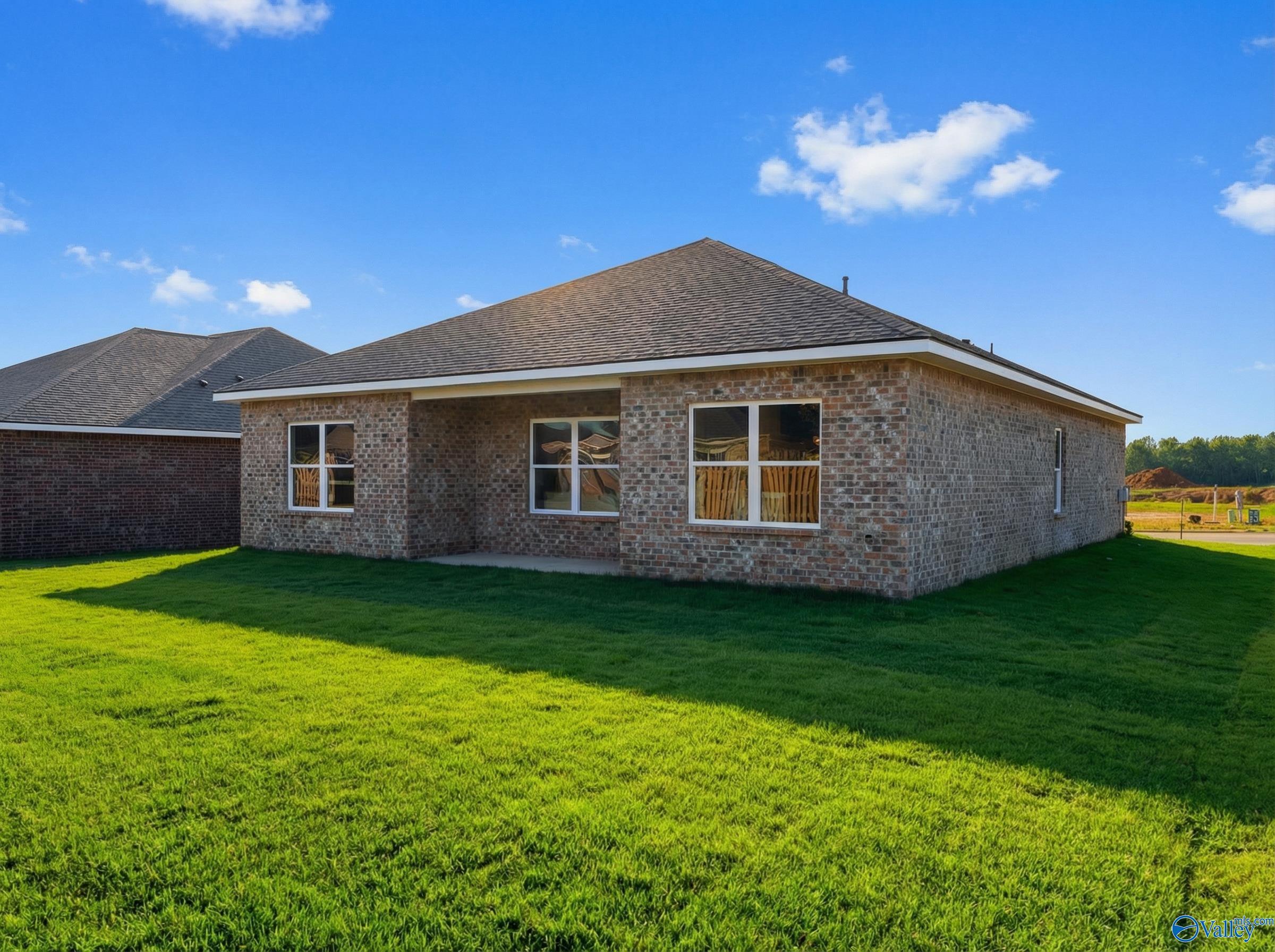 Brick single-story home with gabled roof, large windows, and covered entry on lush green lawn in Wood Trail, Toney, Alabama - Davidson Homes The Asheville