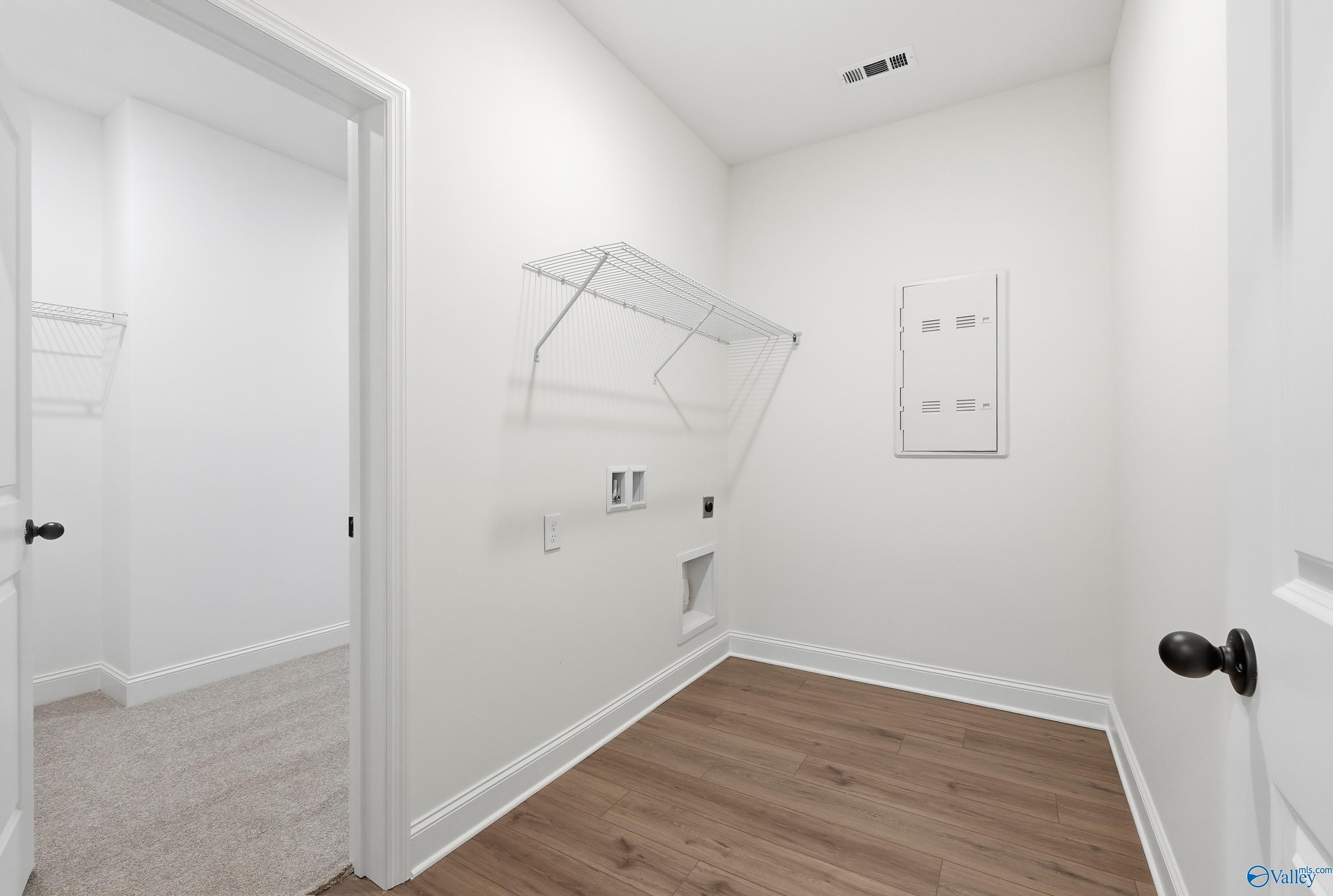 Bright laundry room featuring utility sink, wire shelving, and hardwood floors in Davidson Homes The Rockford D, Hazel Green, AL