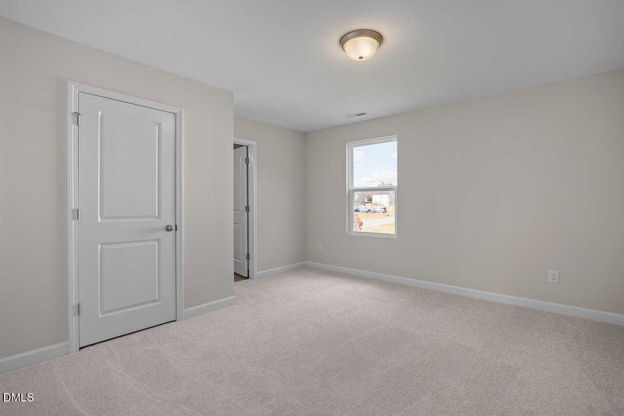 Bright secondary bedroom with beige walls, white doors, large window in Davidson Homes The Gavin C, Lillington, NC