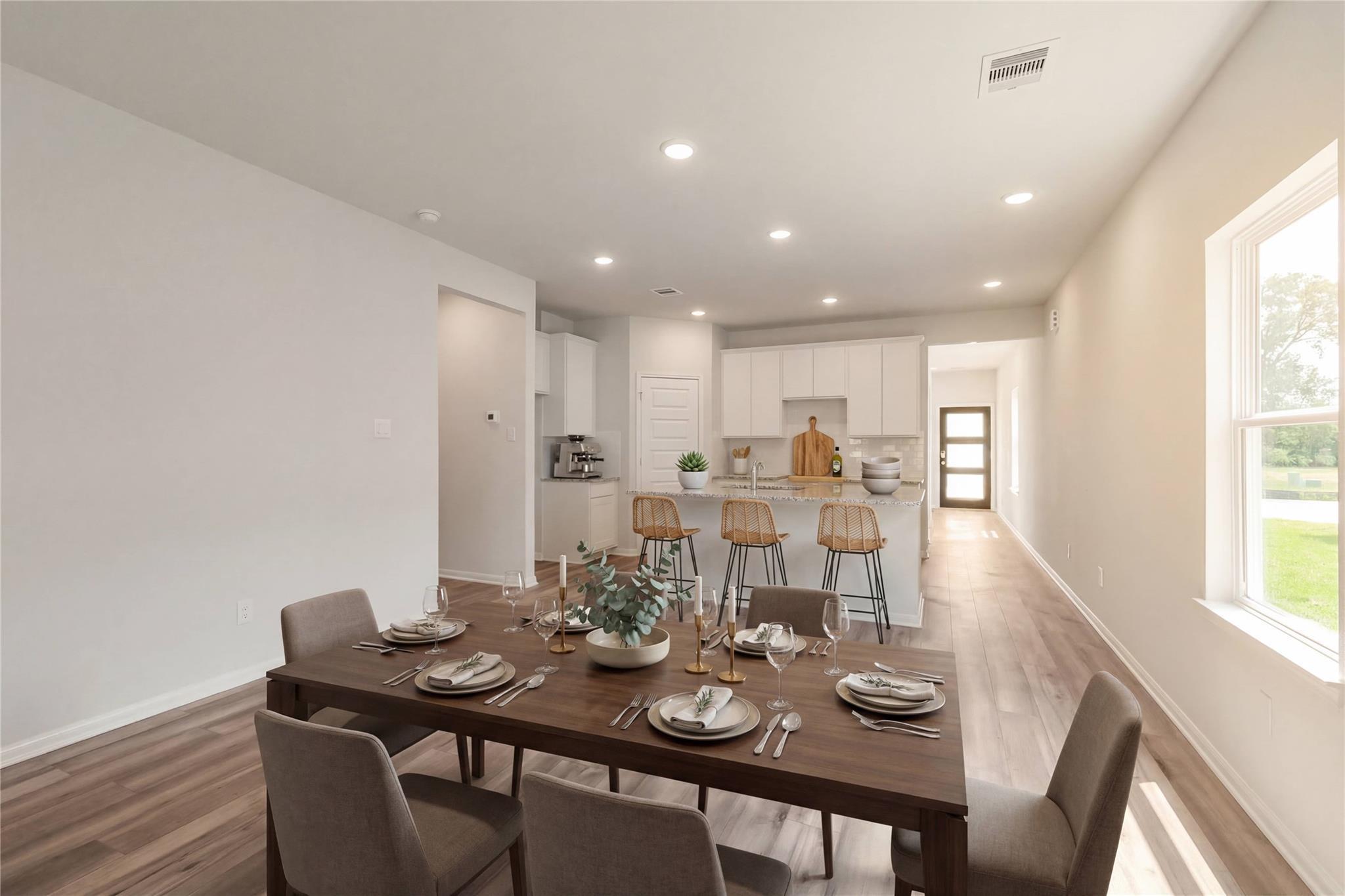 Elegant open dining area with set wooden table, upholstered chairs, and kitchen island in The Sabine E, Conroe, Texas