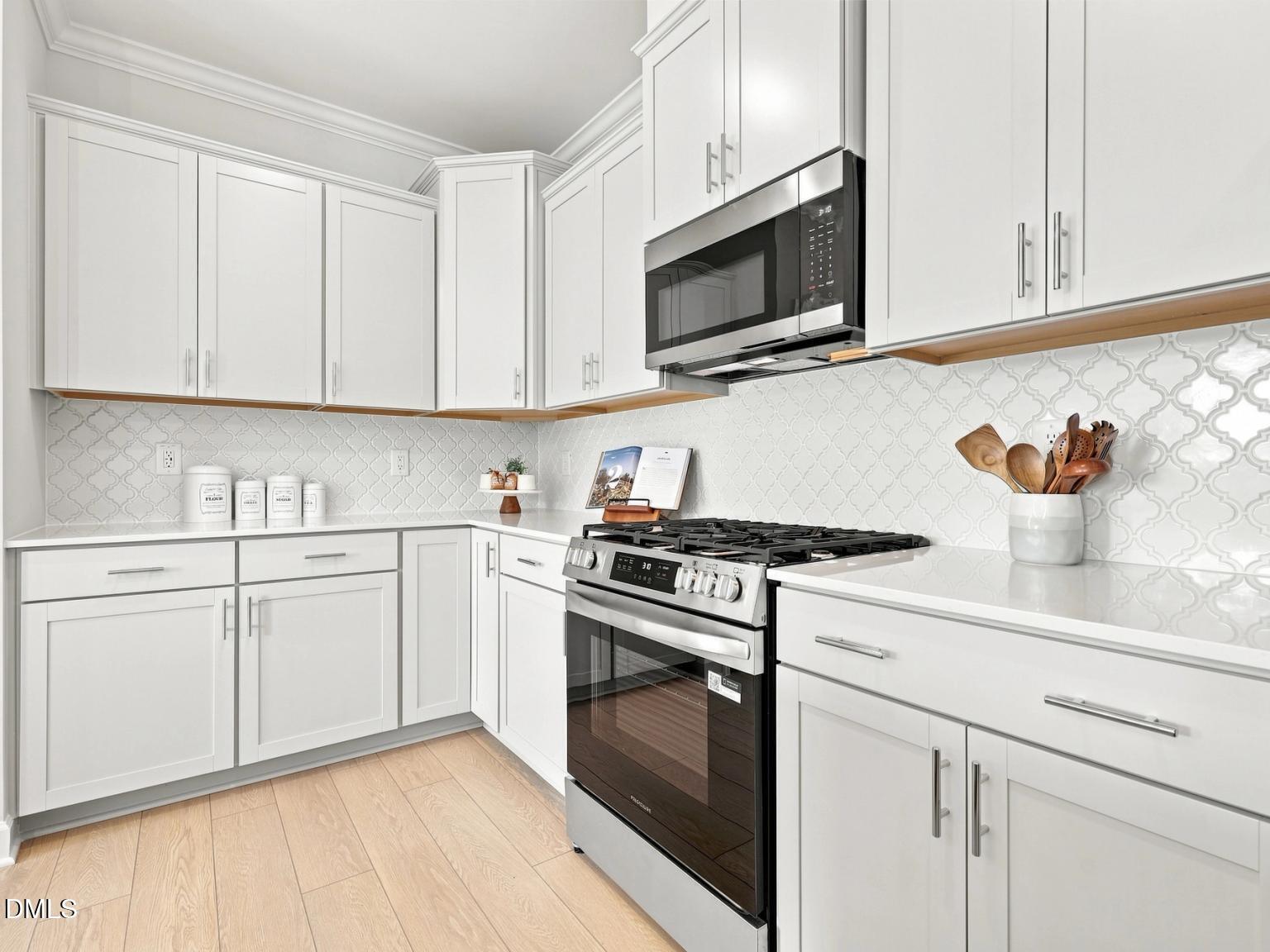 Modern kitchen with white cabinets, gas range, and tile backsplash in The Daphne C floor plan, Woodland Crossing, Zebulon.