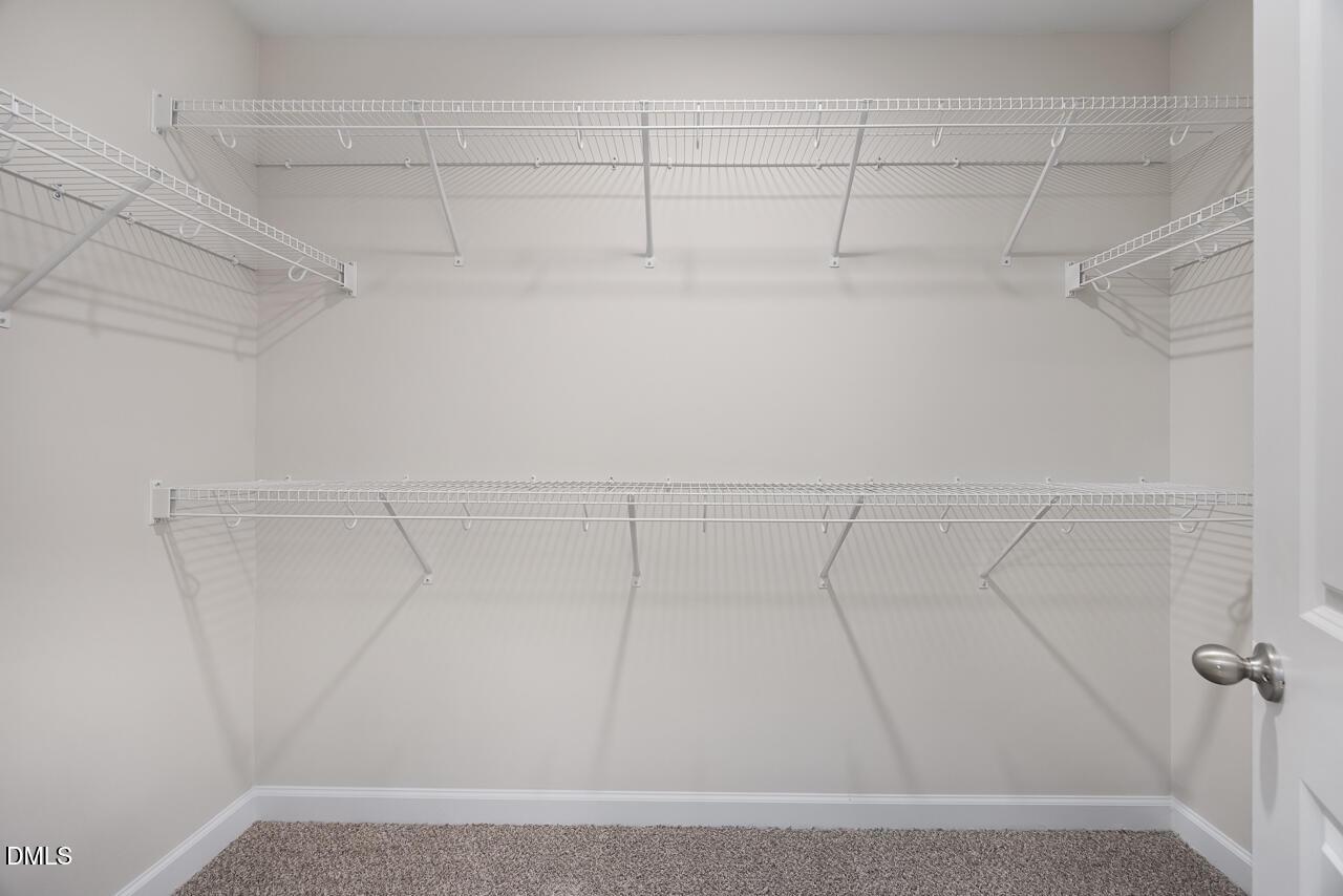 Spacious walk-in closet with multi-level white wire shelving in Davidson Homes The Grace C, Lillington, NC