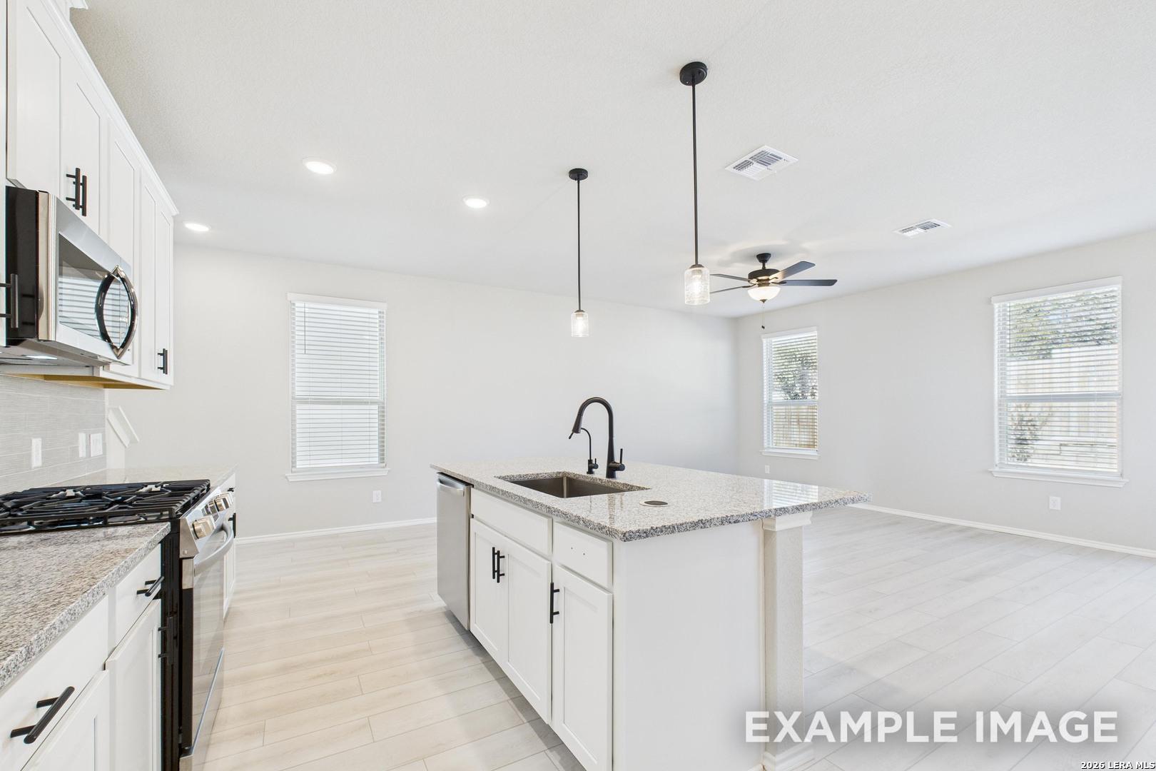 Modern kitchen with granite island and white cabinets in The Charlotte B floor plan at Cedar Heights, San Antonio, Texas.