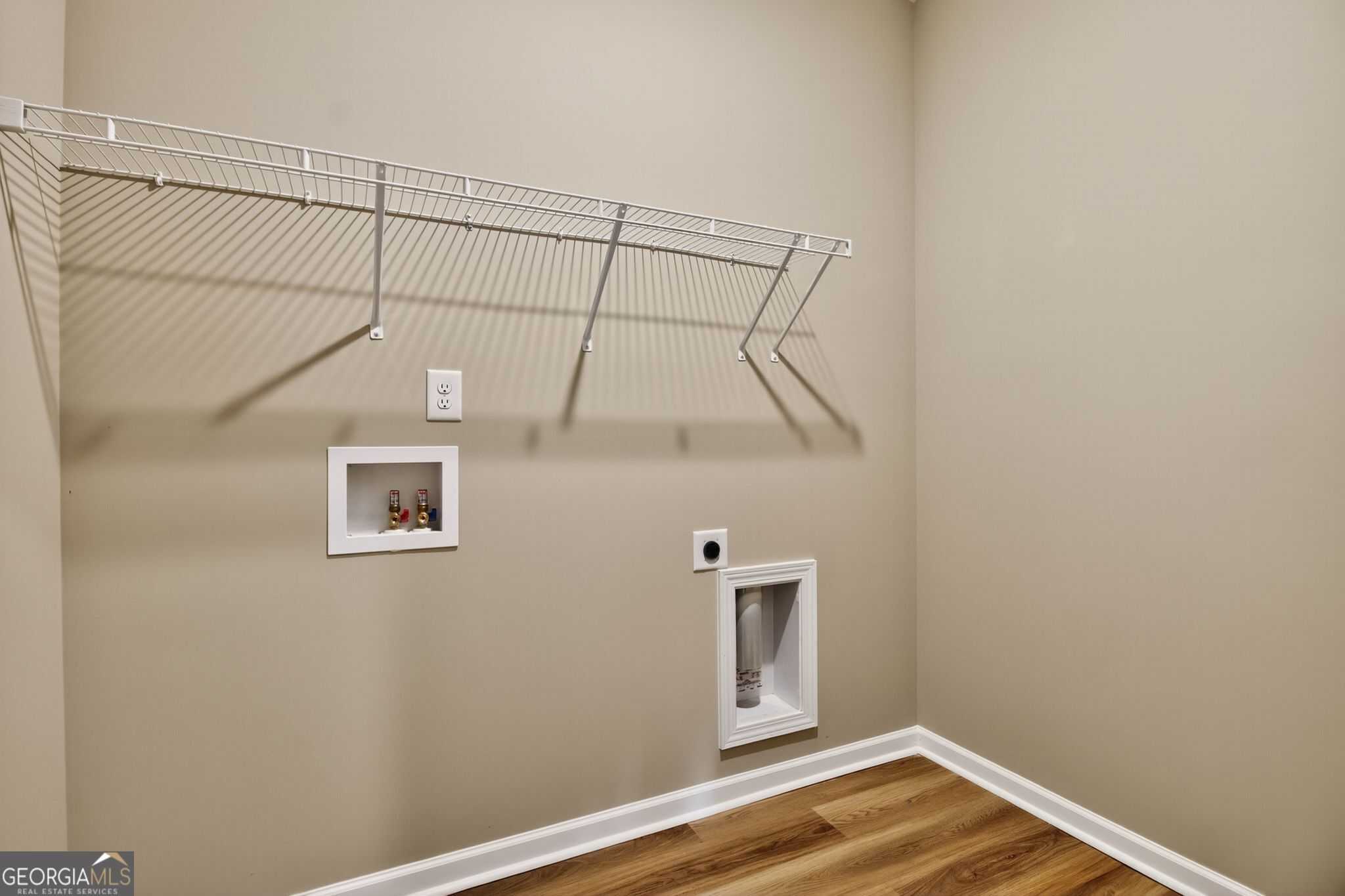Spacious laundry room with white wire shelving, recessed detergent shelf, dryer vent and outlet in Evermore Homes The Luna, Perry, Georgia