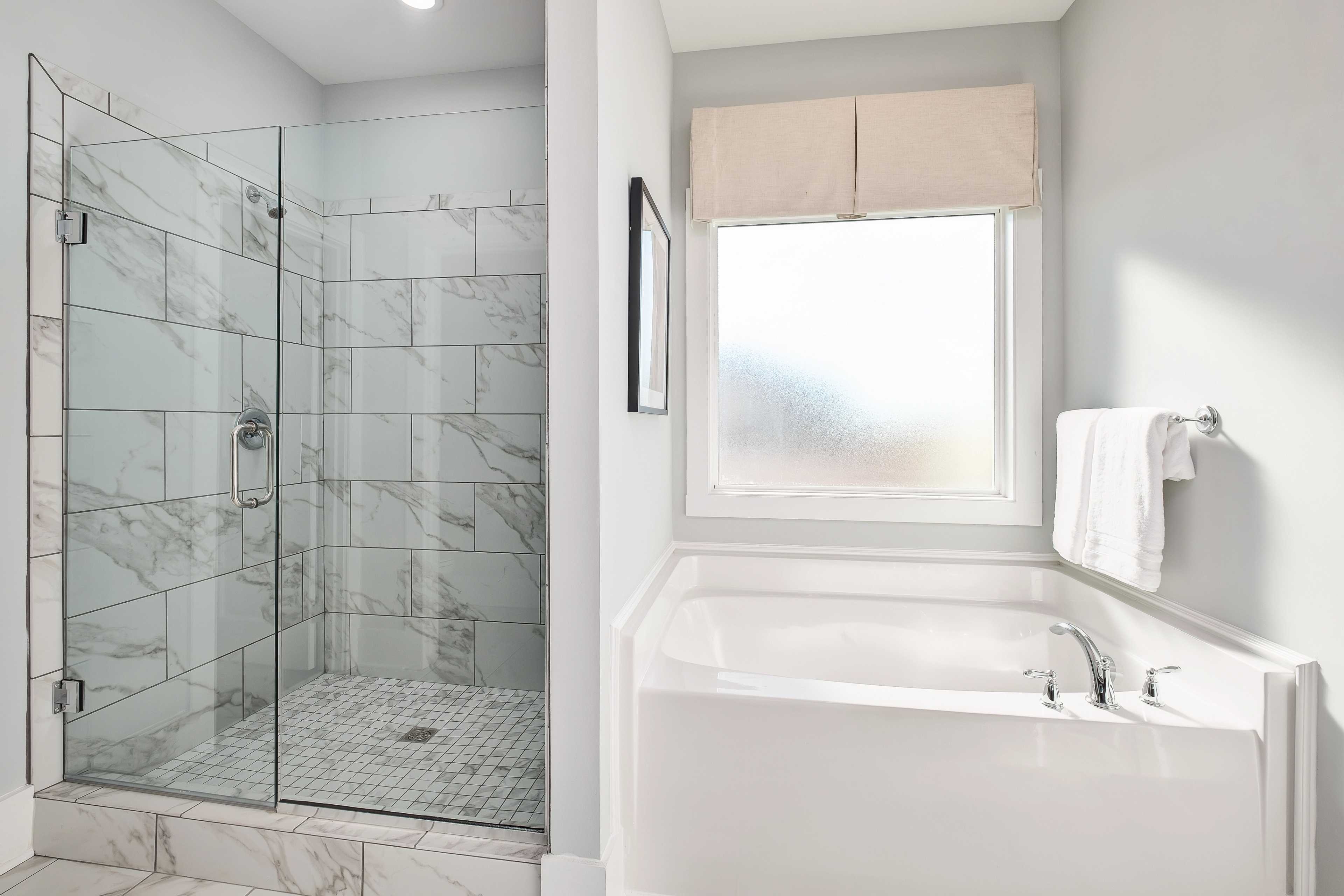 Spacious master bathroom at Mallard Landing in Athens Alabama with glass shower, marble tiles, and soaking tub