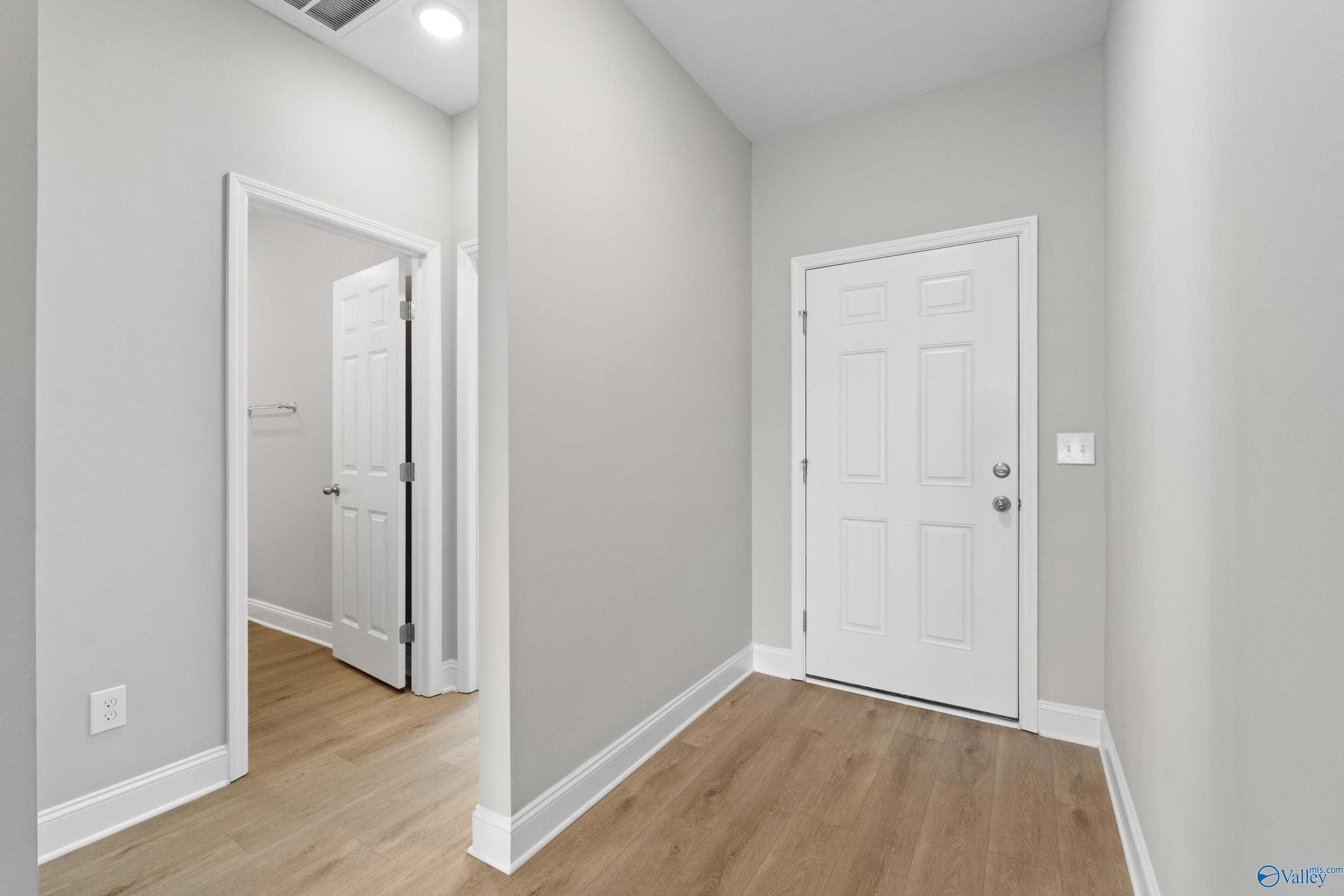 Bright hallway with gray walls, hardwood floors, and white doors in The Asheville C home, The Meadows, Athens, Alabama