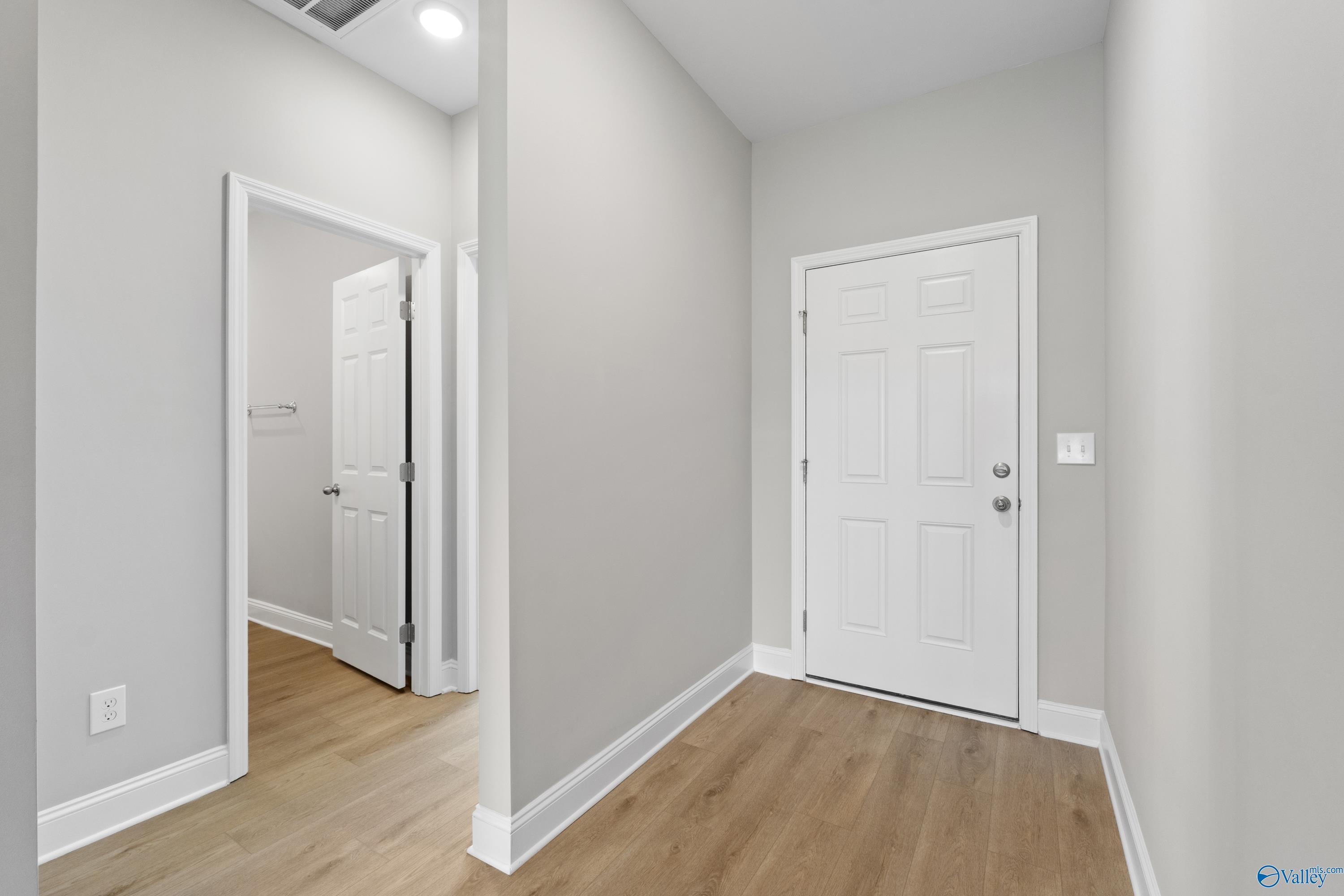Bright hallway with gray walls, hardwood floors, and white doors in The Asheville C home, The Meadows, Athens, Alabama