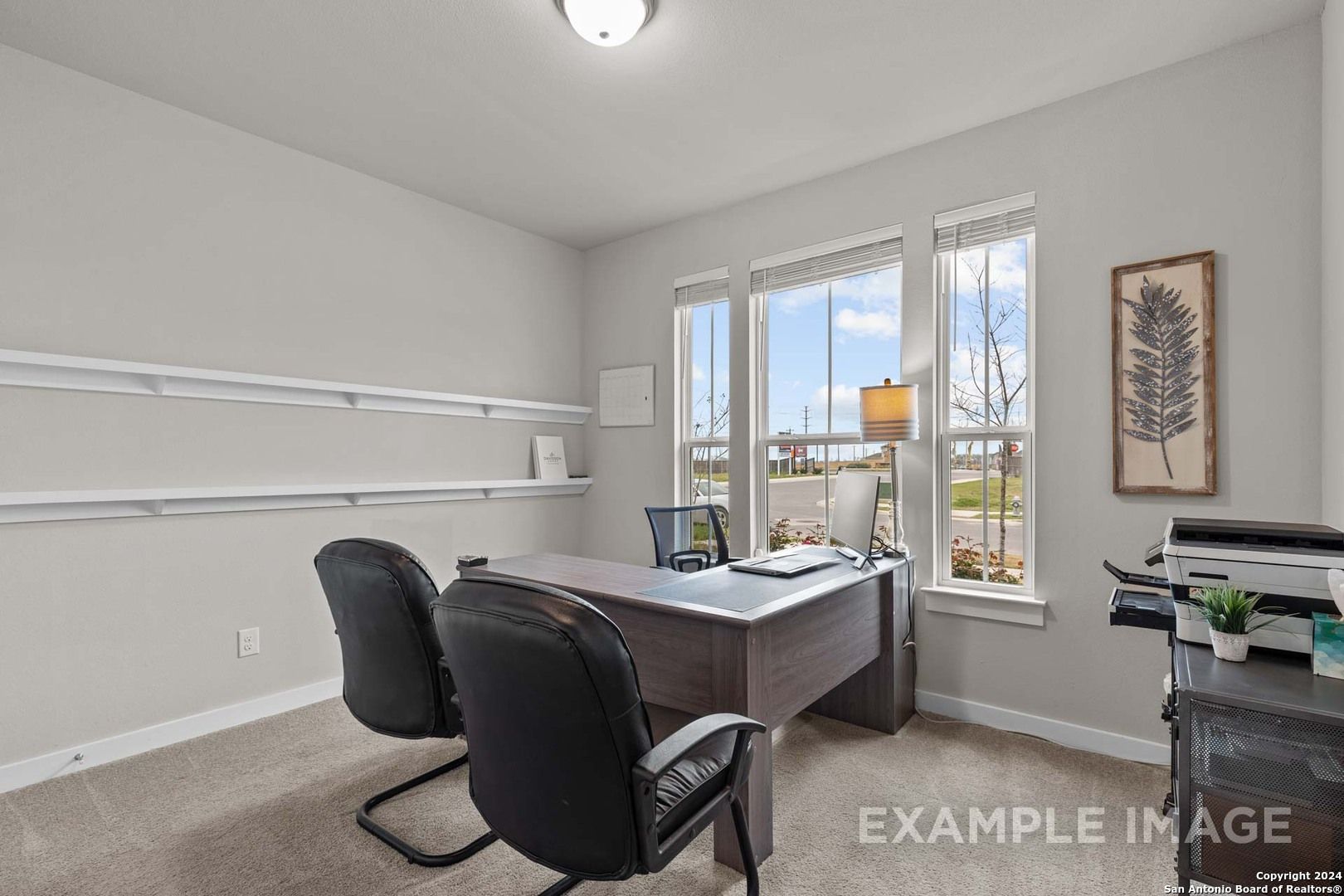 Modern home office with executive wooden desk, black leather chairs, large windows, and wall shelves in The Collin A, Seguin, Texas