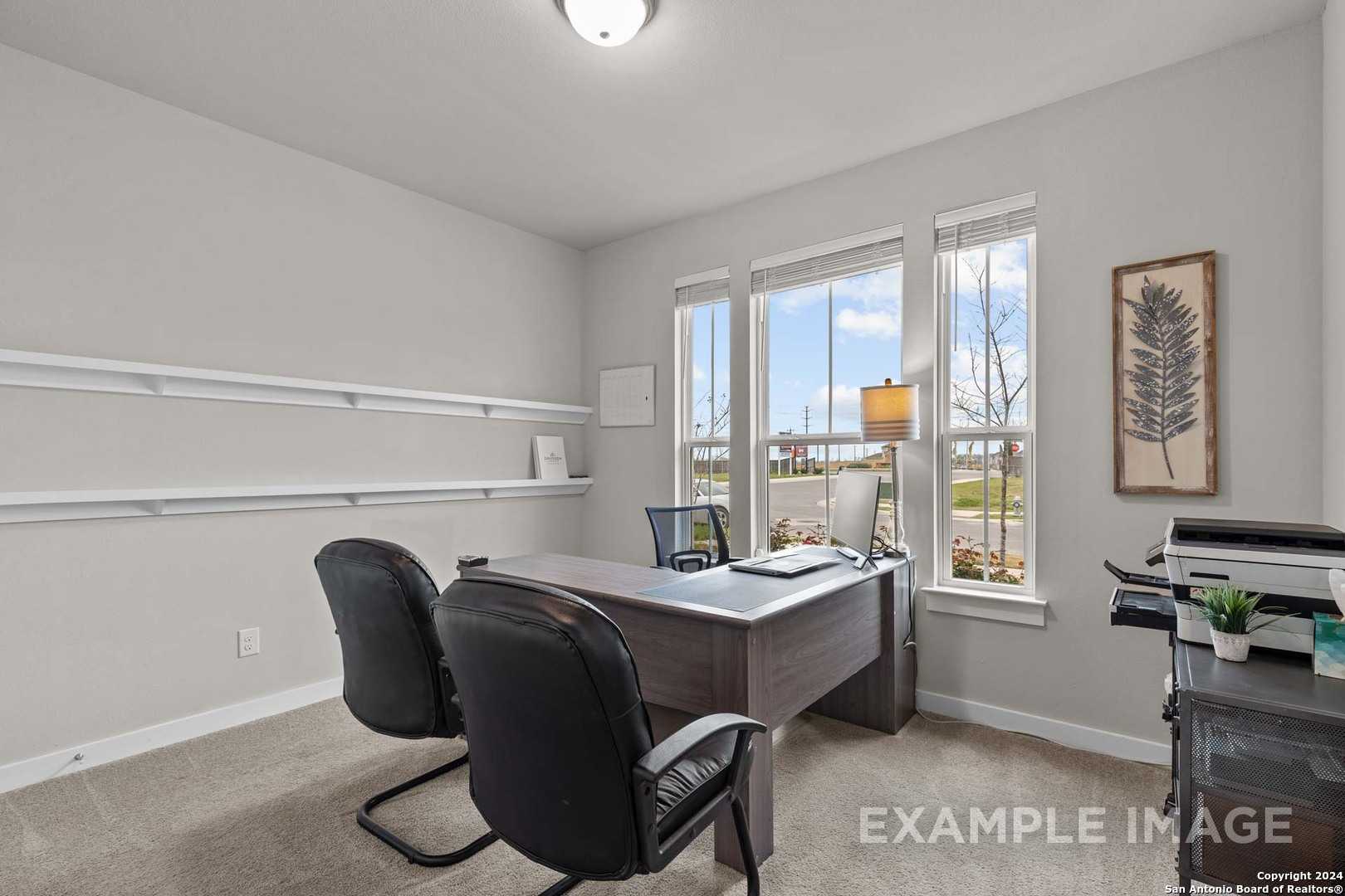 Modern home office with executive wooden desk, black leather chairs, large windows, and wall shelves in The Collin A, Seguin, Texas