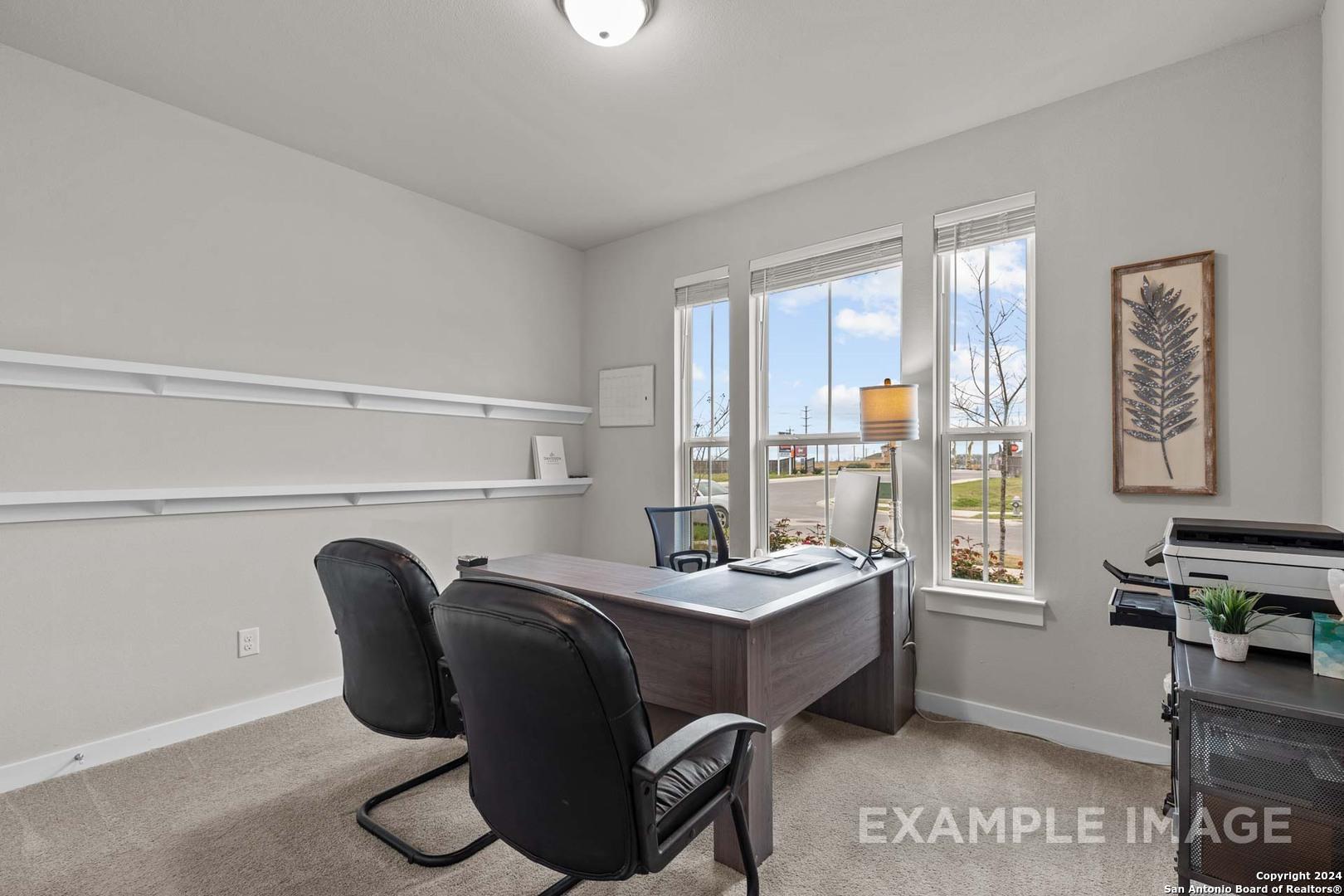 Modern home office with executive wooden desk, black leather chairs, large windows, and wall shelves in The Collin A, Seguin, Texas