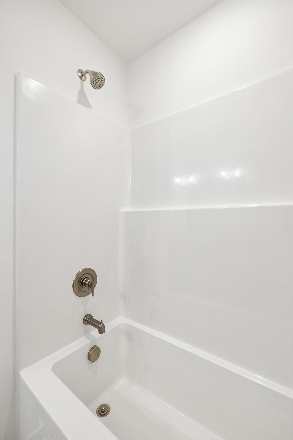 Modern white bathtub with brushed nickel showerhead and faucet in Davidson Homes The Willow bathroom, Calista Farms, White House, TN