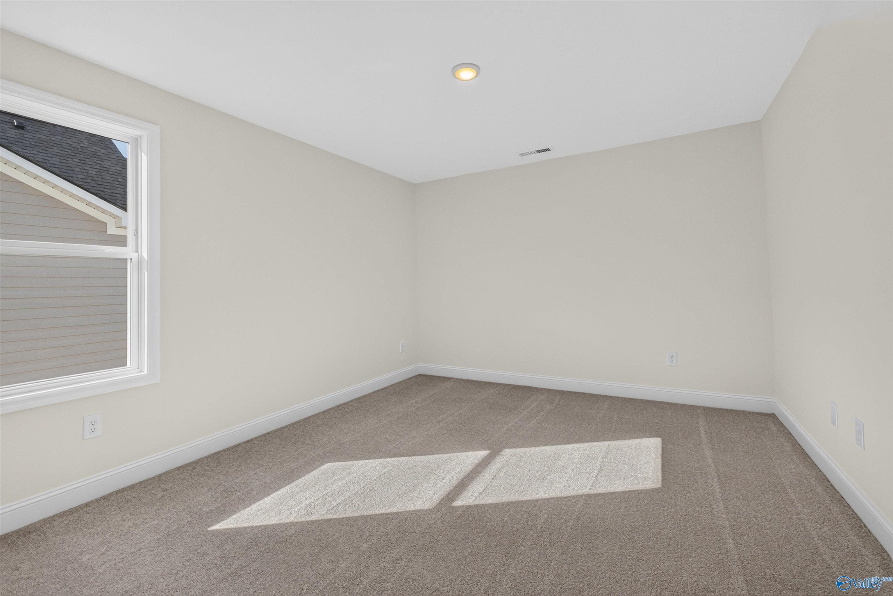 Bright empty bedroom with plush carpet, white trim, and natural light in Davidson Homes Ashport L plan, Berry Cove, New Market, AL